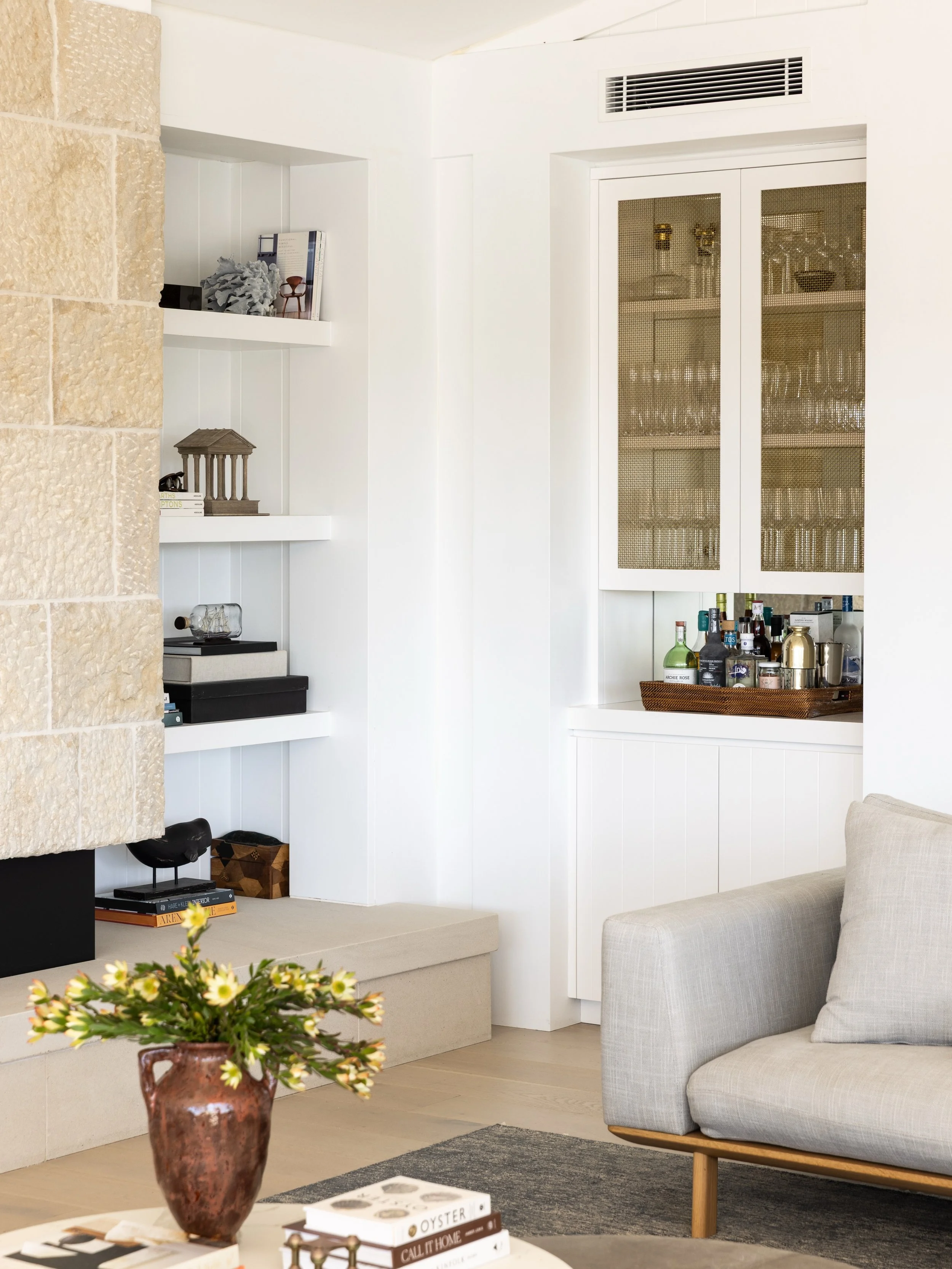 A textural stone fireplace and tailored joinery create a cosy retreat for cooler evenings. Project @strittdesignandconstruction. Photography @simonwhitbreadphoto. Styling @olgalewisstyling. #chinamansbeachhouse #strittdesignandconstruction