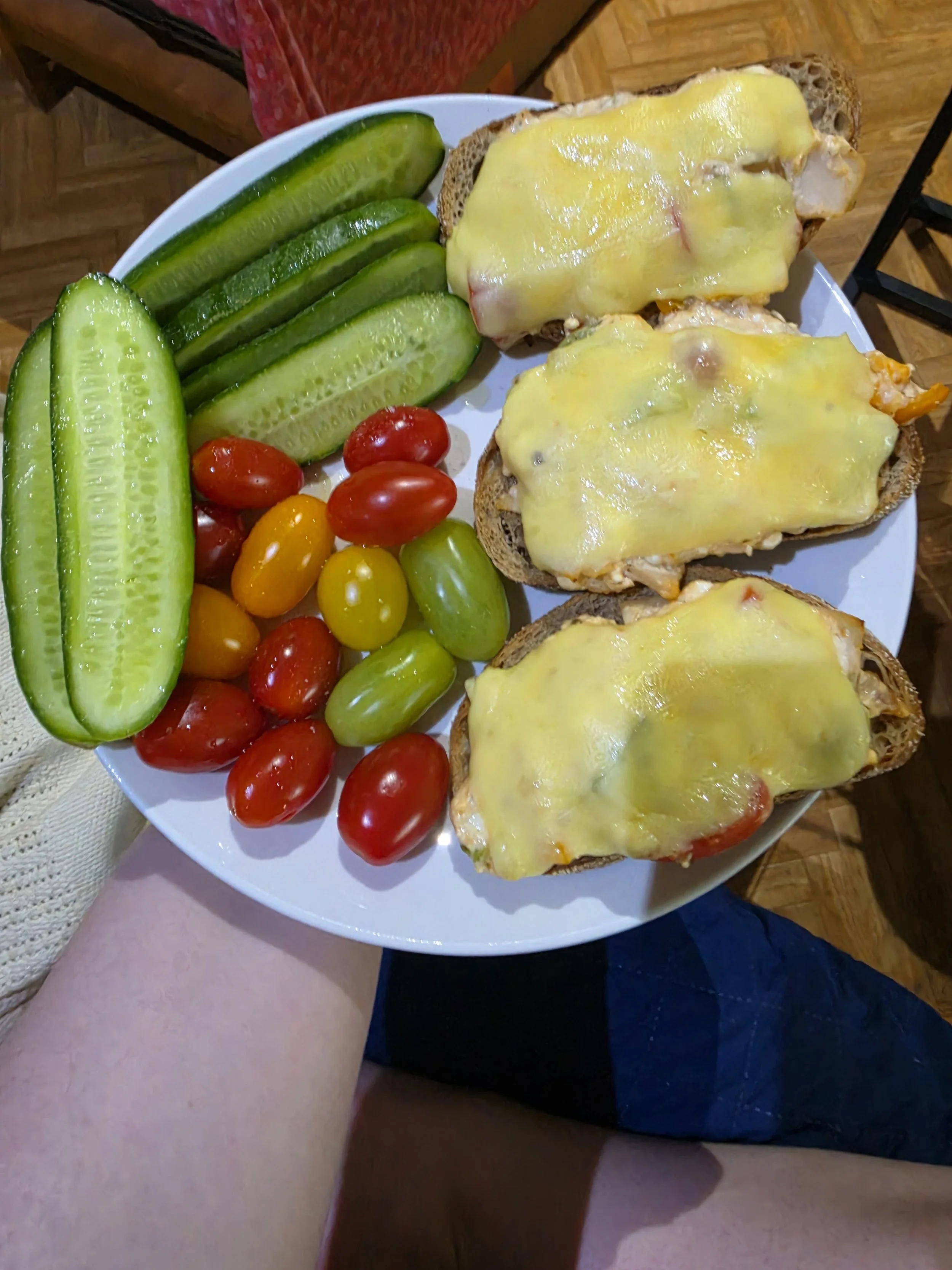Hand holding out plate of cottage cheese toast and cucumbers and tomatoes with extra virgin olive oil and salt.