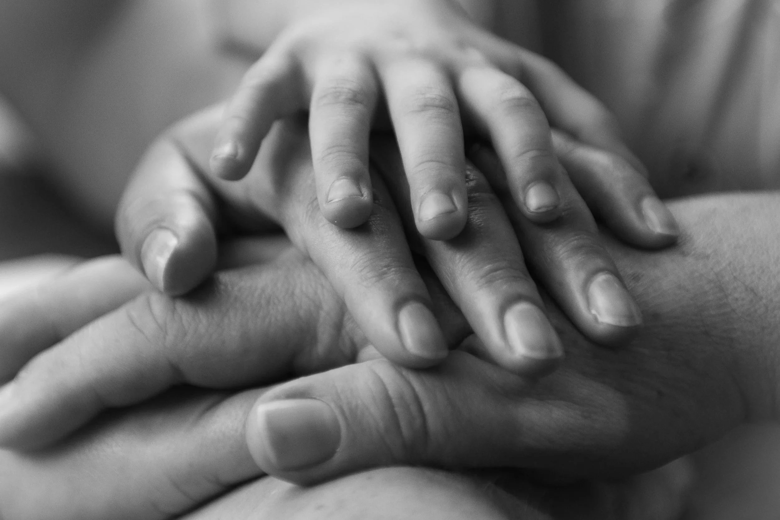 Family members placing their hands together in a show of unity and support.
