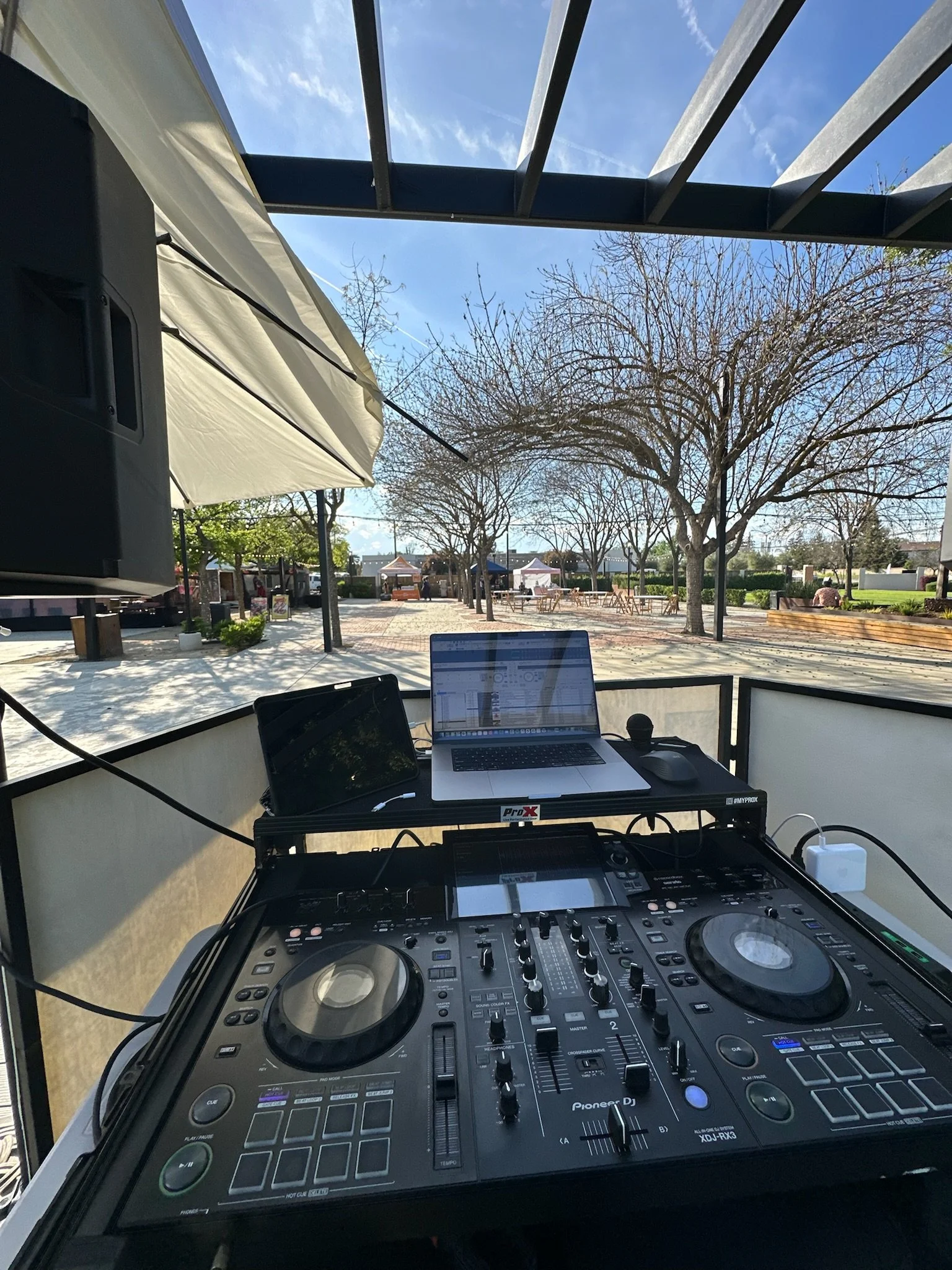 DJ equipment set up outdoors with trees and blue sky in the background