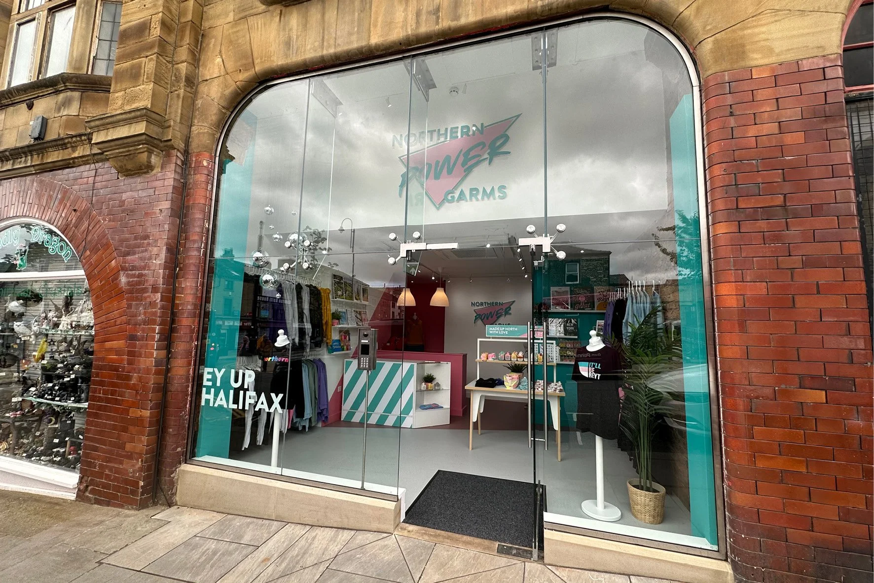 storefront of Northern Power Garms, a clothing store with glass windows displaying clothing and accessories, featuring a sign with the store's name and logo inside.