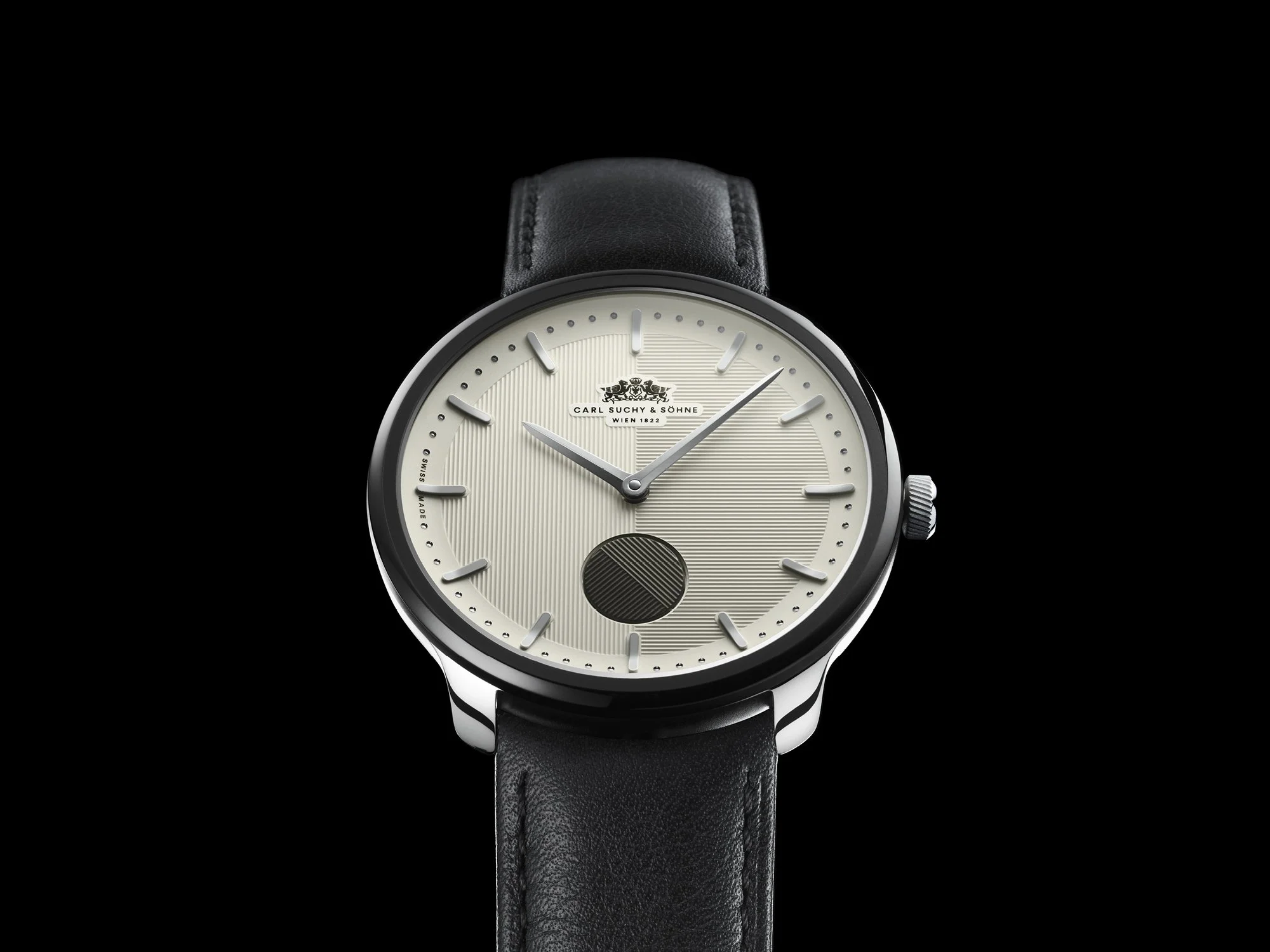 A luxury wristwatch with a black leather strap, silver case, and a cream dial featuring minimalist hour markers, with the brand name 'Carl Suchy & Söhne' on the face.