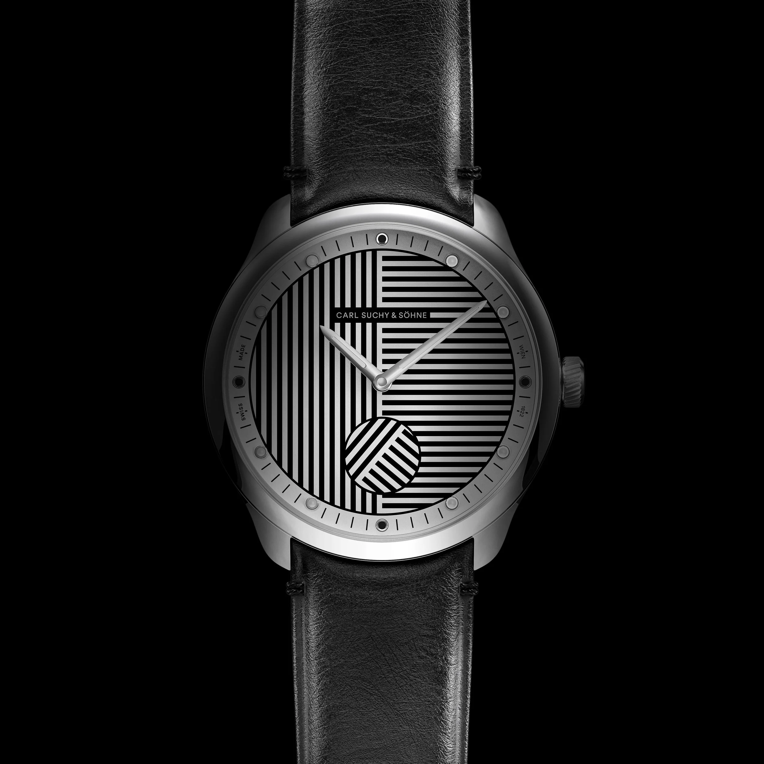 A black leather strap watch with a black and white striped patterned face, brand name Carl Suchy & Söhne, silver hour and minute hands.