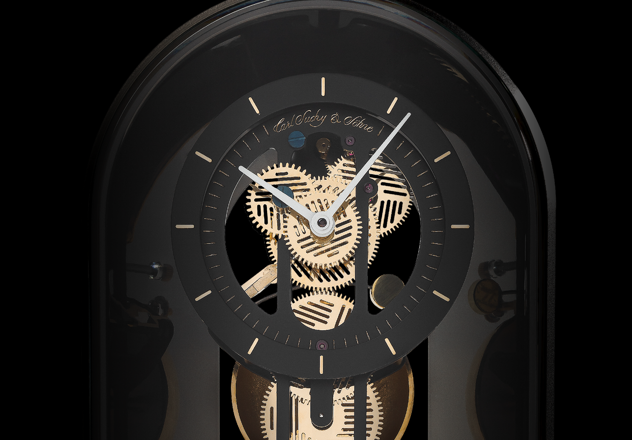 Close-up of a black and gold mechanical clock with visible gears, black face, and white hands showing the time, set against a black background.