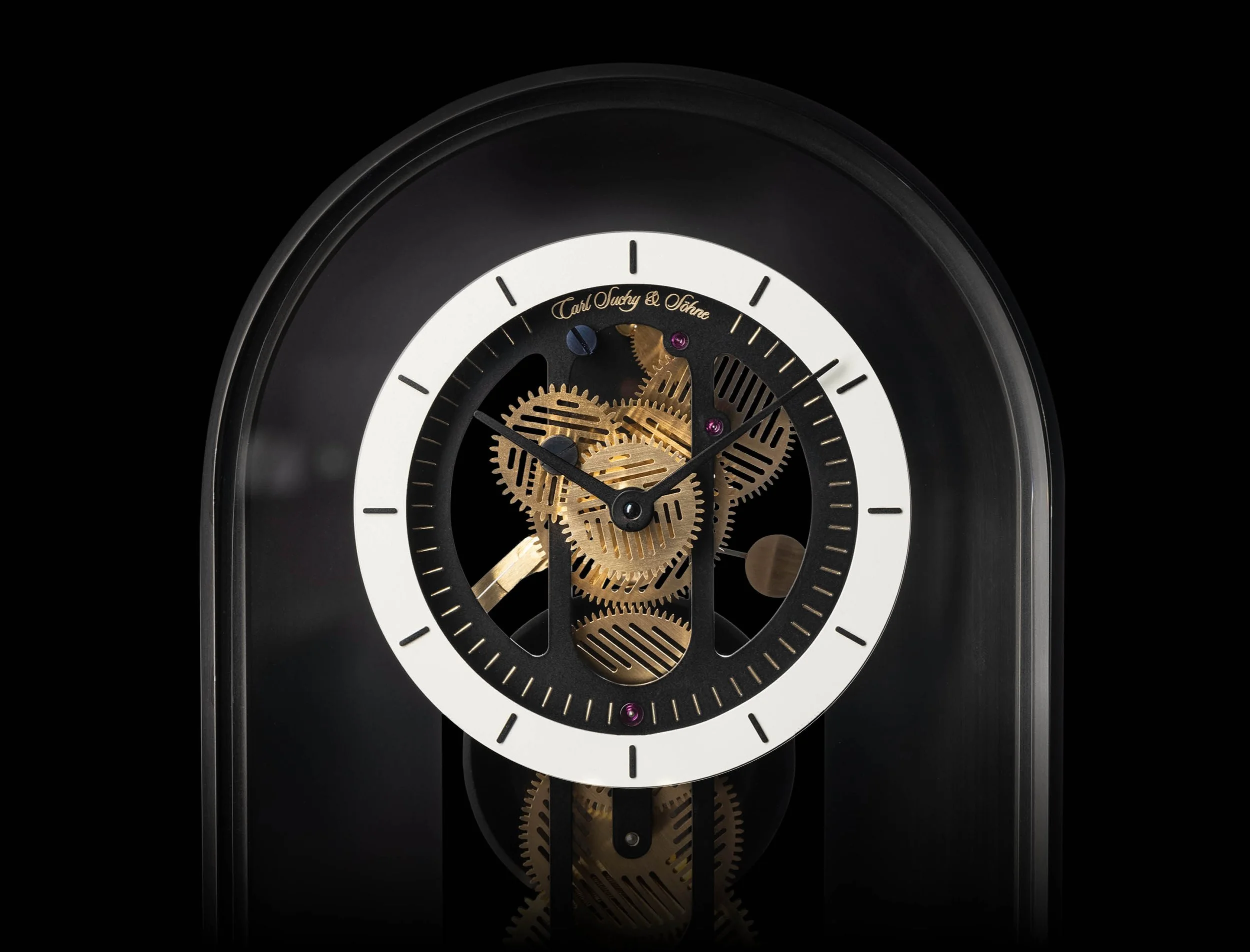 A close-up view of a black and white mechanical clock with visible gold gears against a black background.