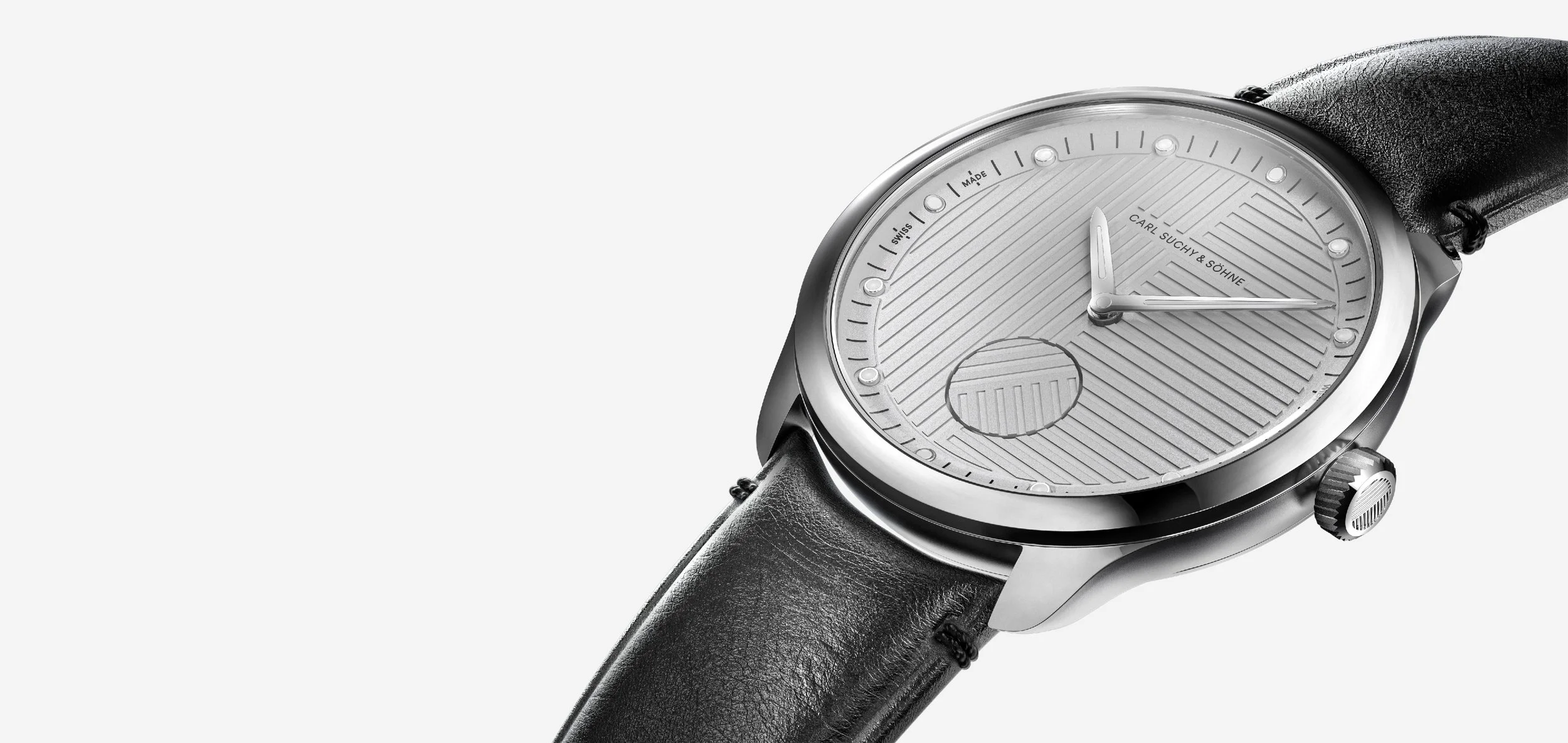 Close-up of a modern men's wristwatch with a black leather strap and a silver dial, featuring textured pattern and minimalistic design.