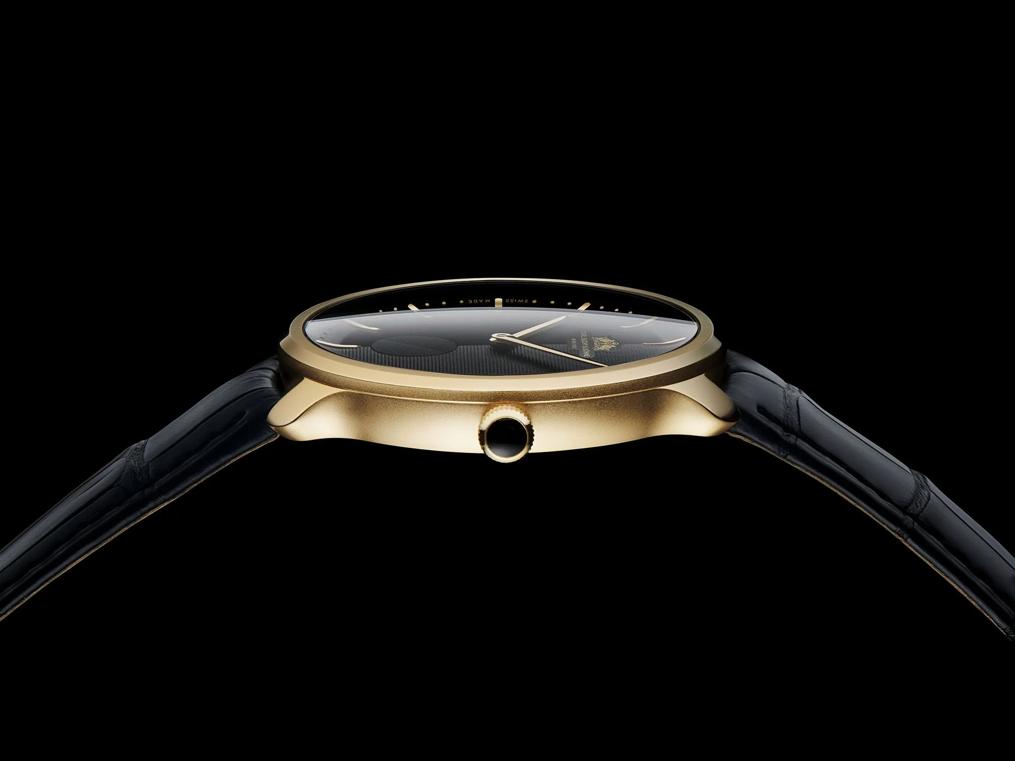 Luxury wristwatch with a black strap, gold case, and black dial, shown from a side angle against a black background.