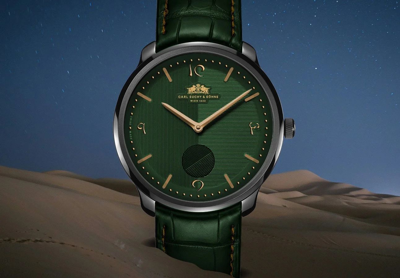 A wristwatch with a green face, gold markers and hands, and a green leather strap, set against a desert landscape under a starry sky.