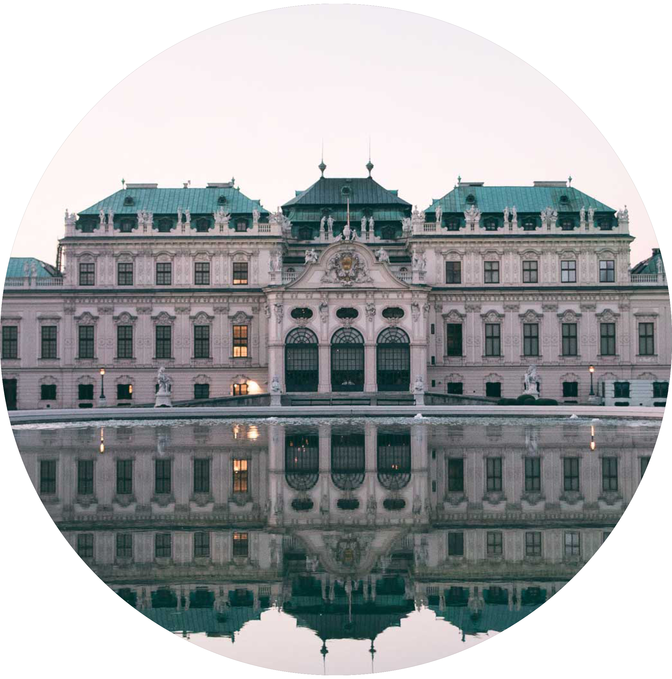 An elegant historic building with ornate architectural details and statues, reflected in the water below, with a gray overcast sky.