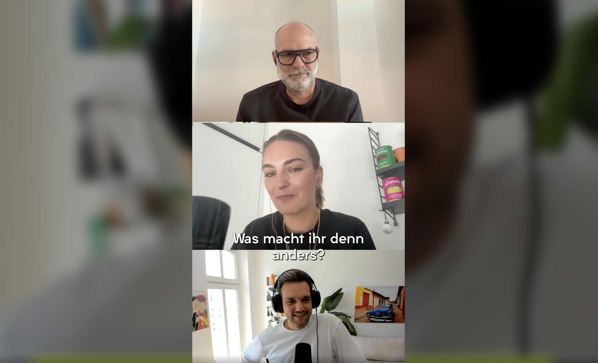 Vier Personen in einem Videoanruf, der in einem virtuellen Meetingraum stattfindet. Die oberste Person ist ein Mann mit Brille und grauem Bart, die zweite Person darunter ist eine Frau mit dunklem Haar, die eine Frage stellt, während die anderen beiden Männer lächeln. Im Hintergrund sind Regale und Fenster sichtbar.