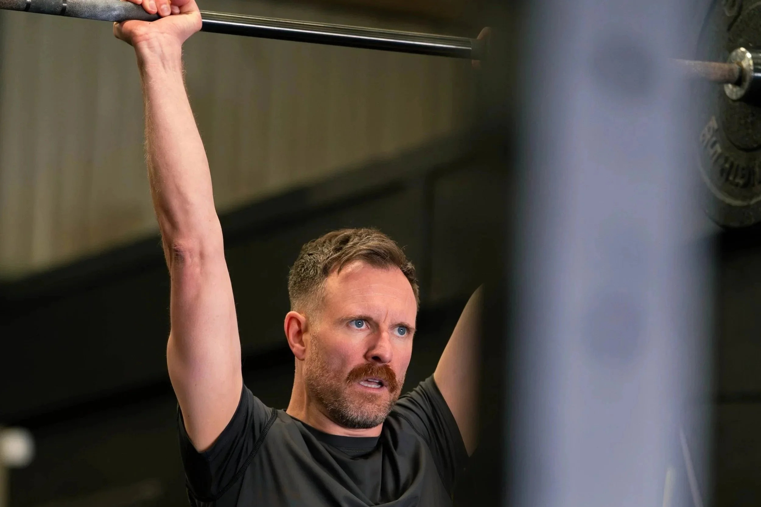 A man holding a barbell above head 