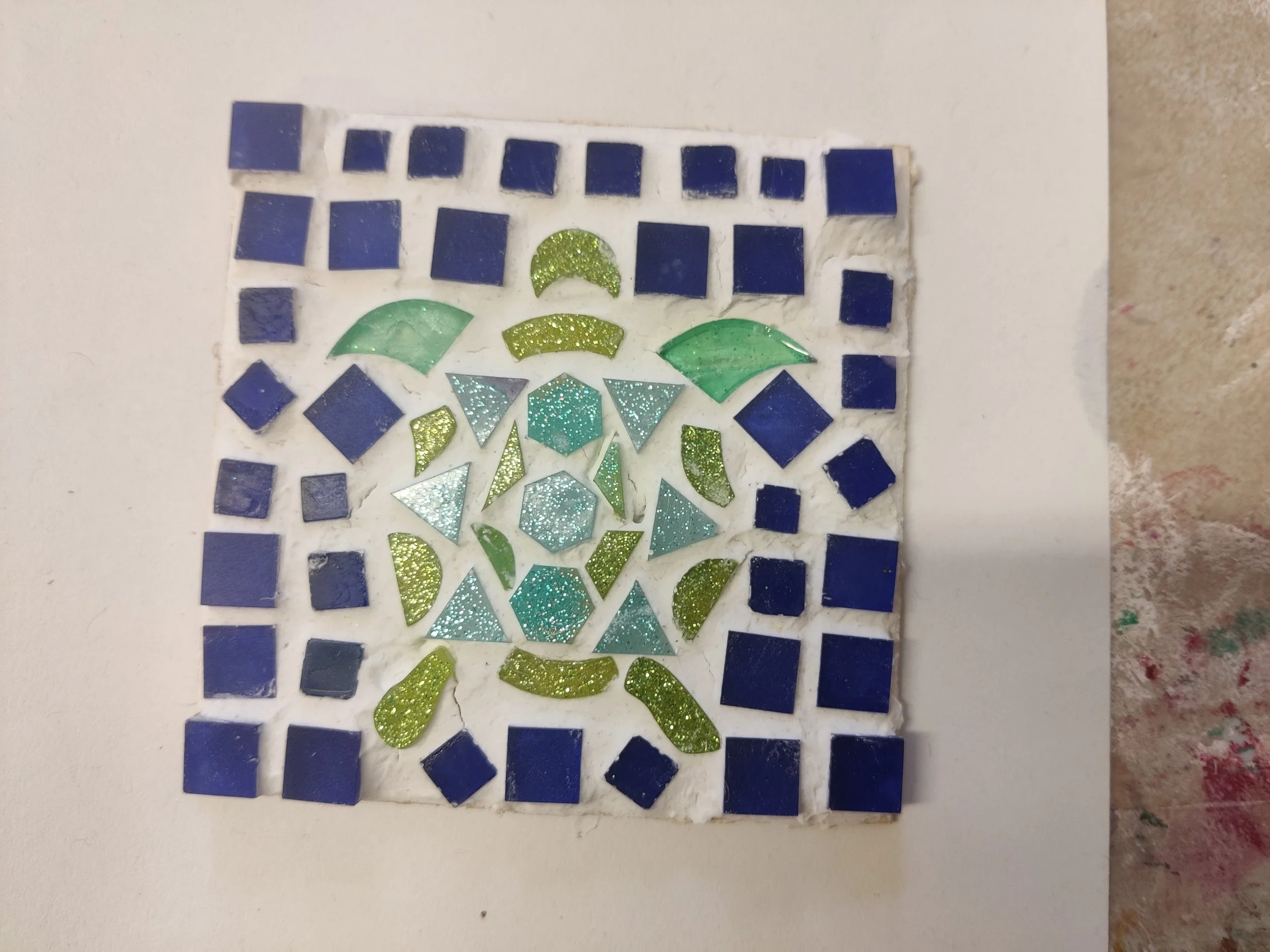 A mosaic of colorful tiles arranged to form an abstract design on a white background.