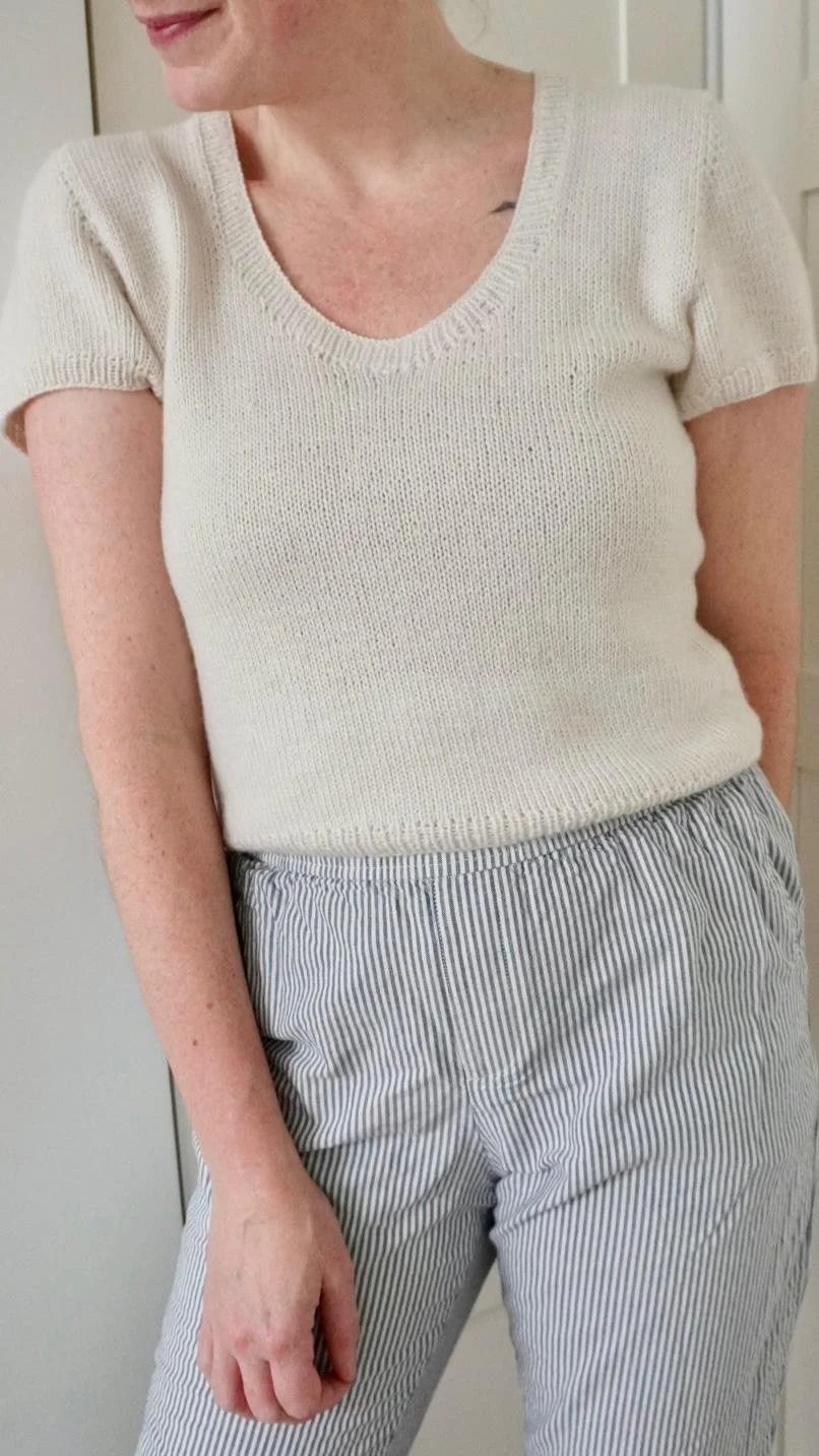 Woman posing with the Cashmere Outside Tee by Arly Knits, and blue pants