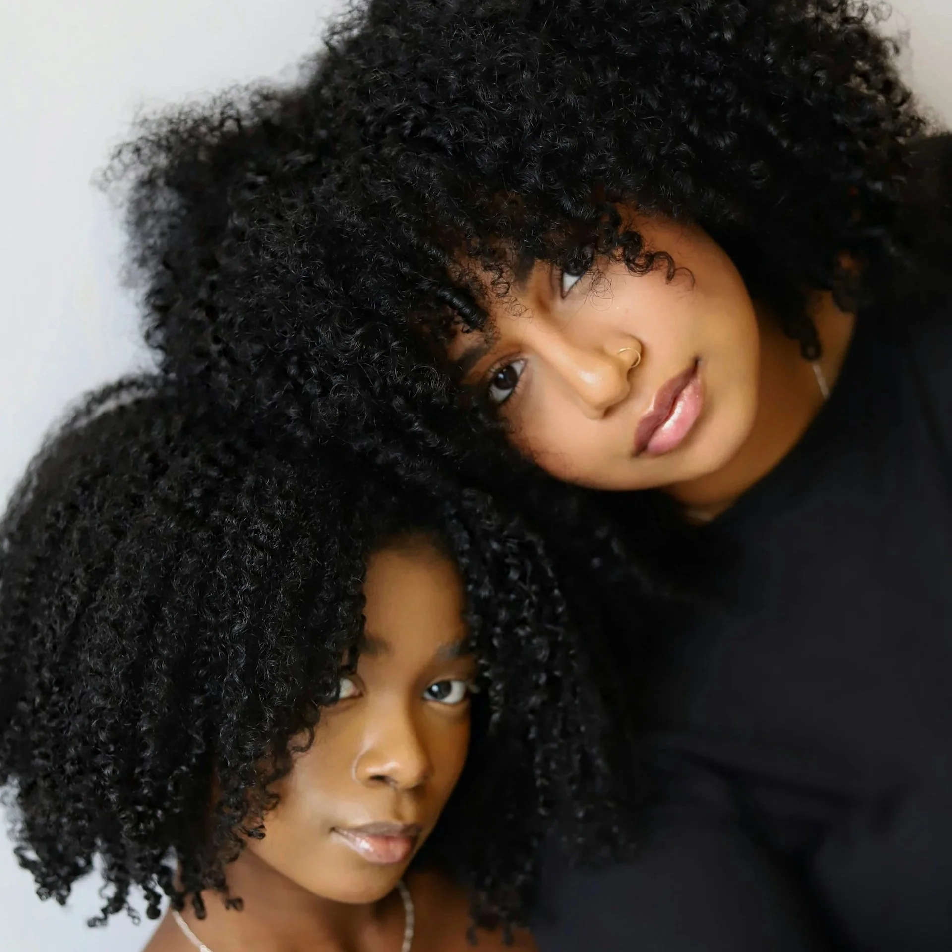 Close-up portrait of two women with dense Type 4a curls and defined natural coil patterns.