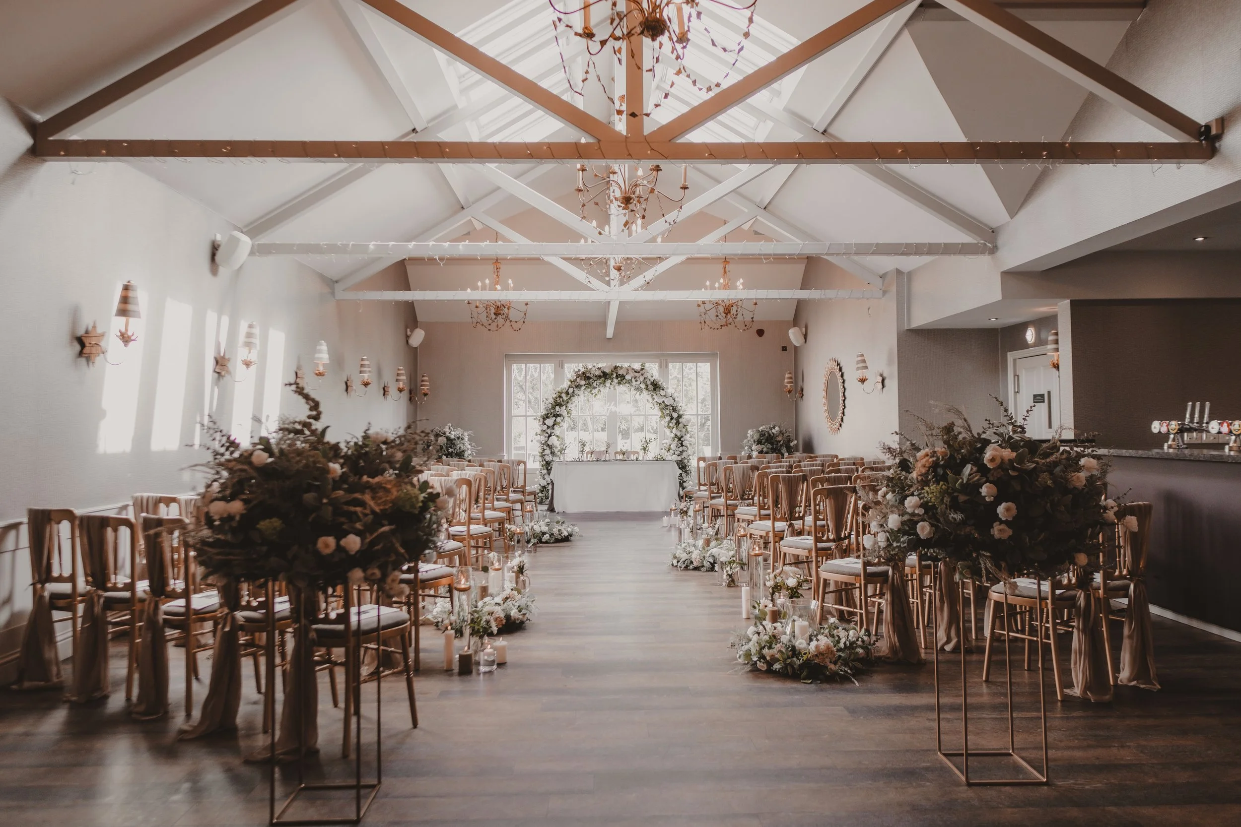 A beautifully decorated wedding ceremony space at Cockliffe Country House with rows of chairs and floral arrangements leading to an arch backdrop.