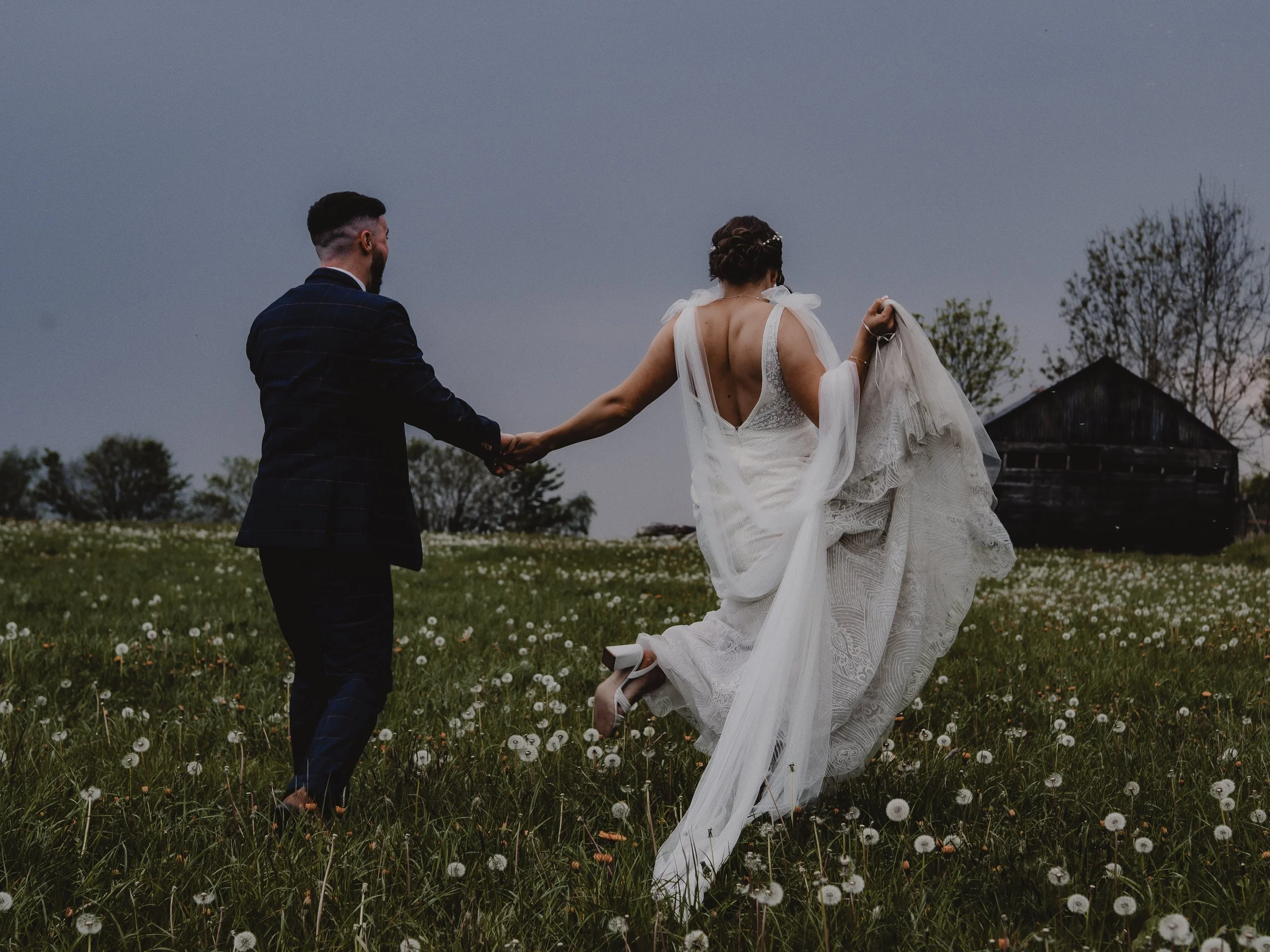 Couple running through the field at sundown