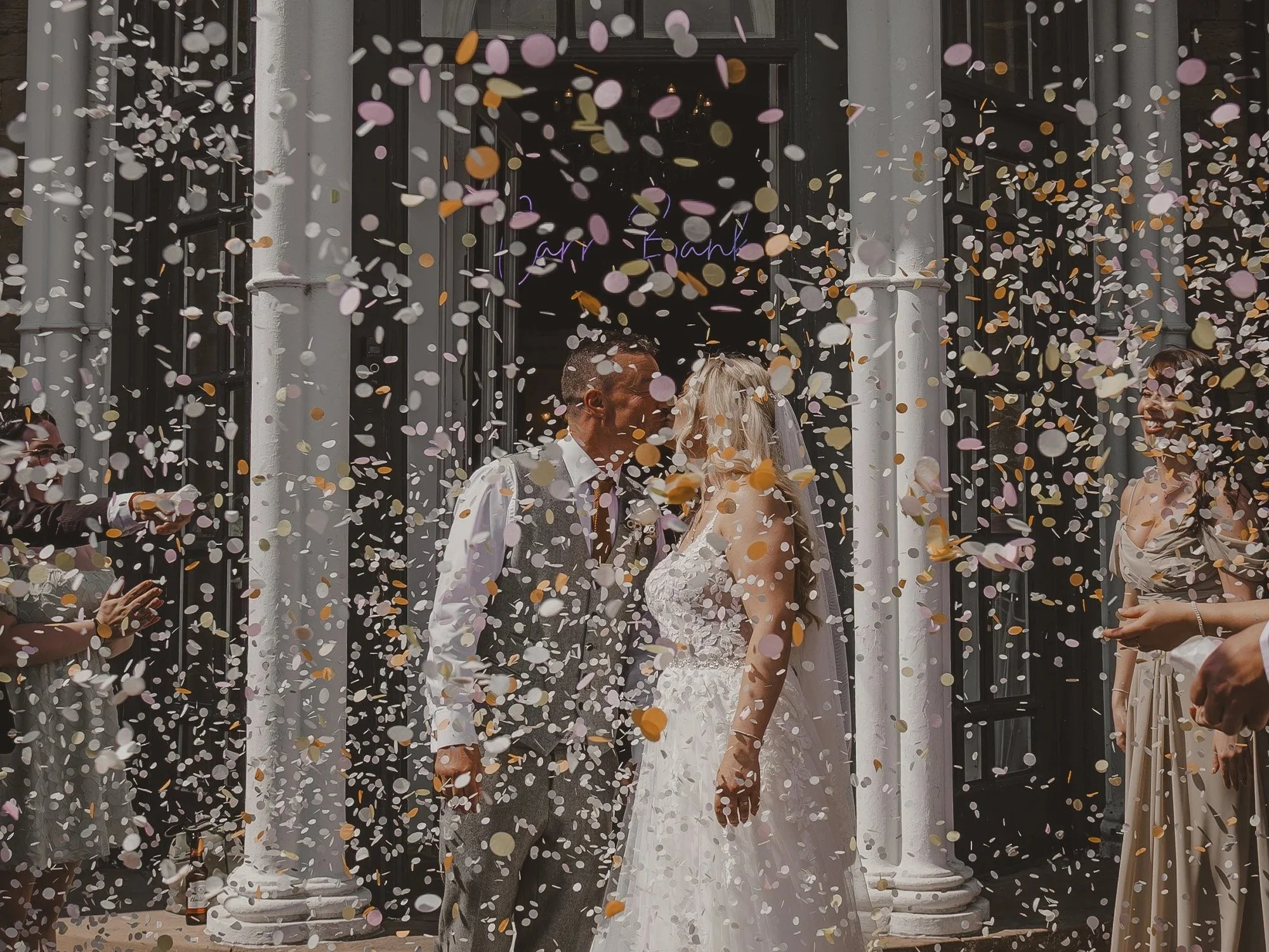 A wedding couple is kissing under falling confetti at Carr Bank Mansfield.