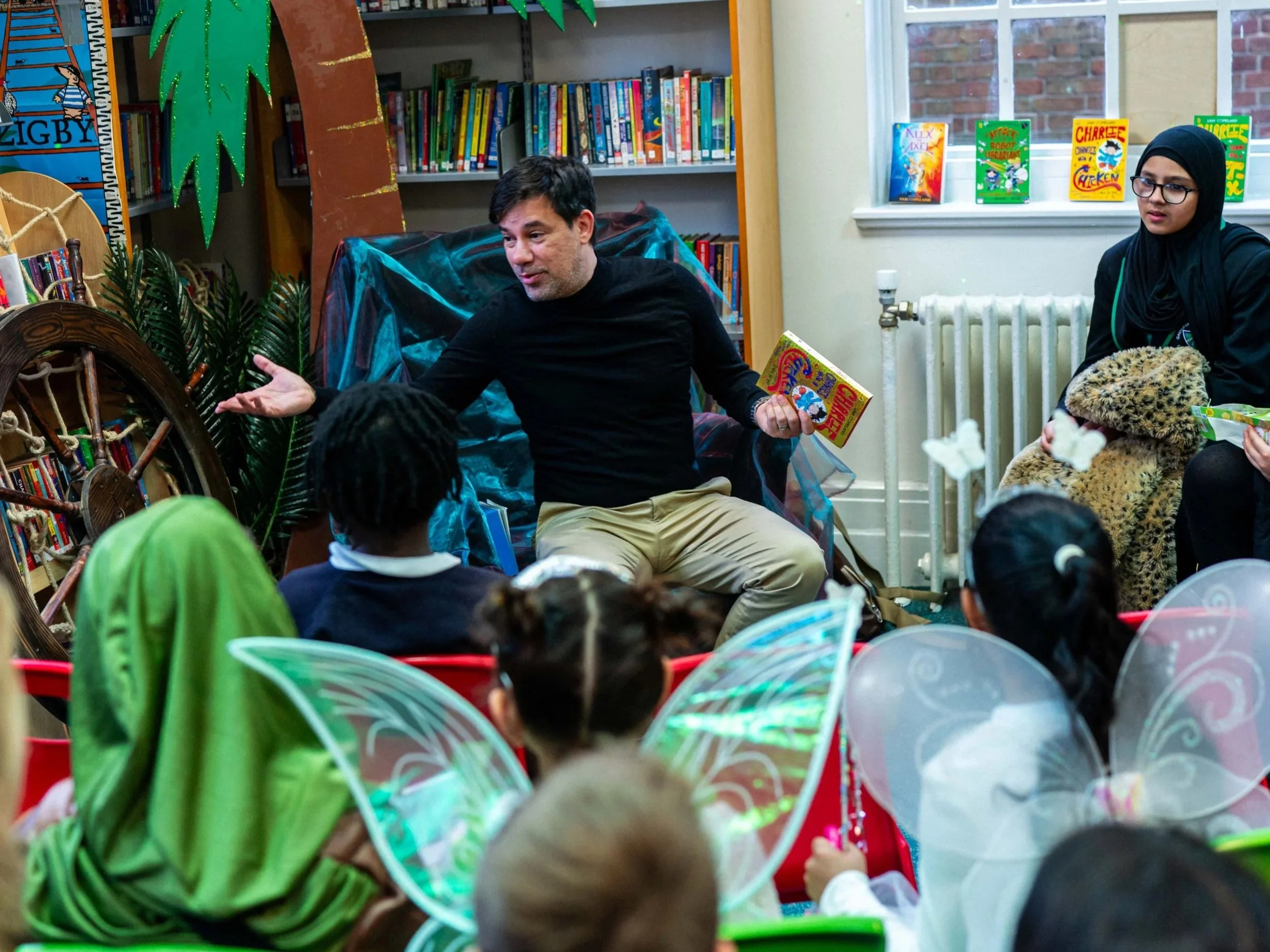 Kids in a library with their hands up