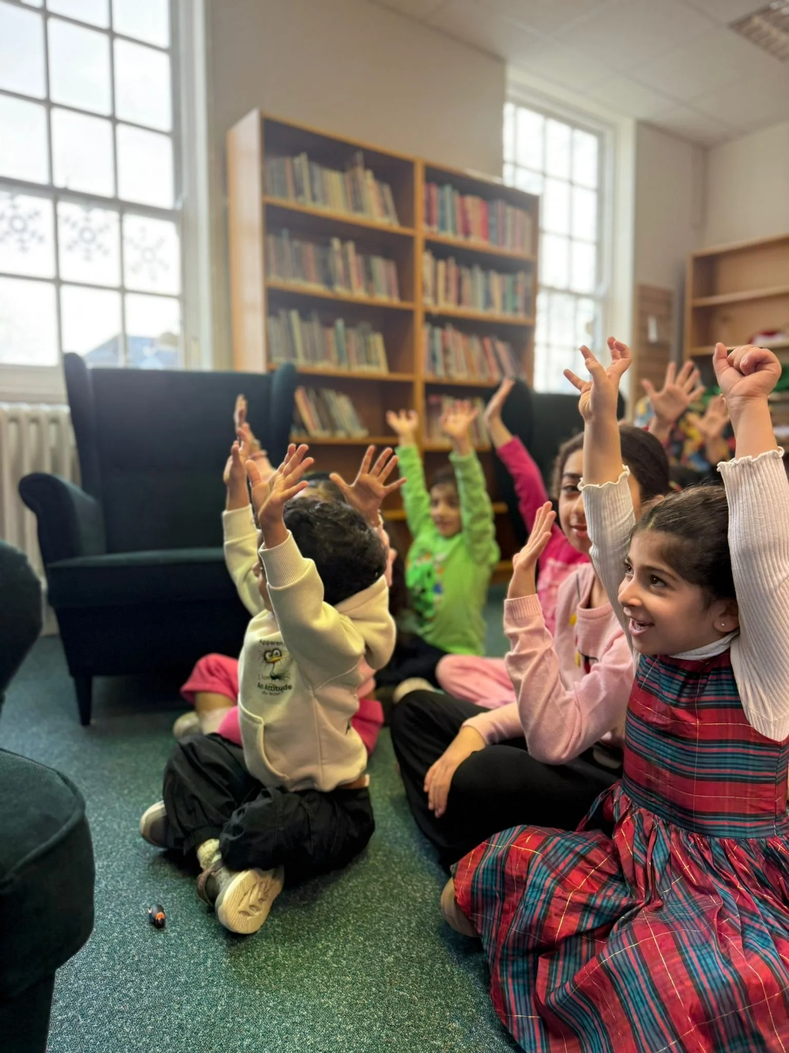 Kids in a library with their hands up