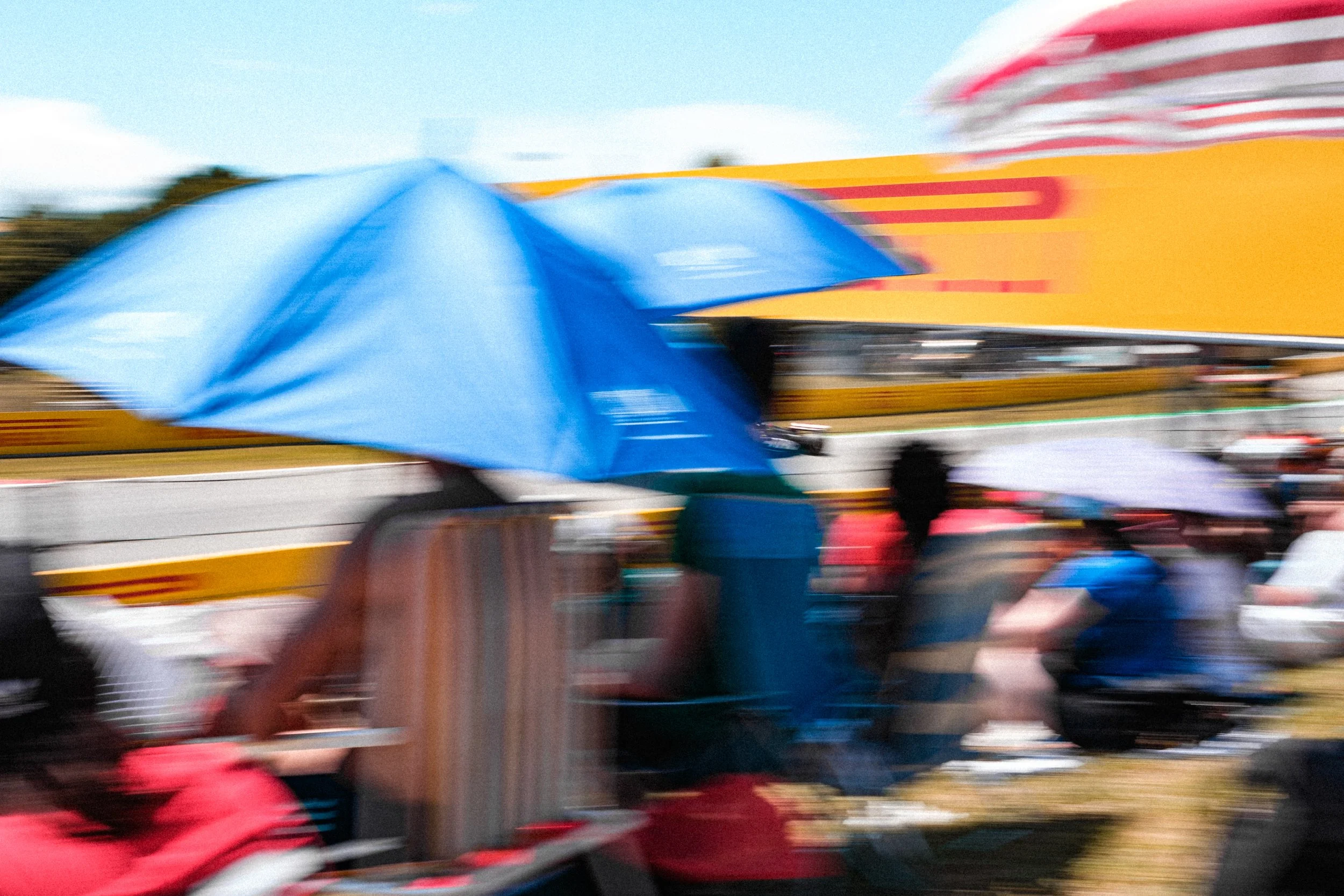 Photo floue d’une course de Formule 1 en Espagne avec des spectateurs sous des parapluies par temps ensoleillé.
