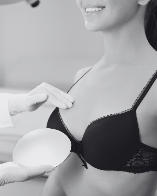 woman in a black bra with a doctor checking her breast and holding an implant option
