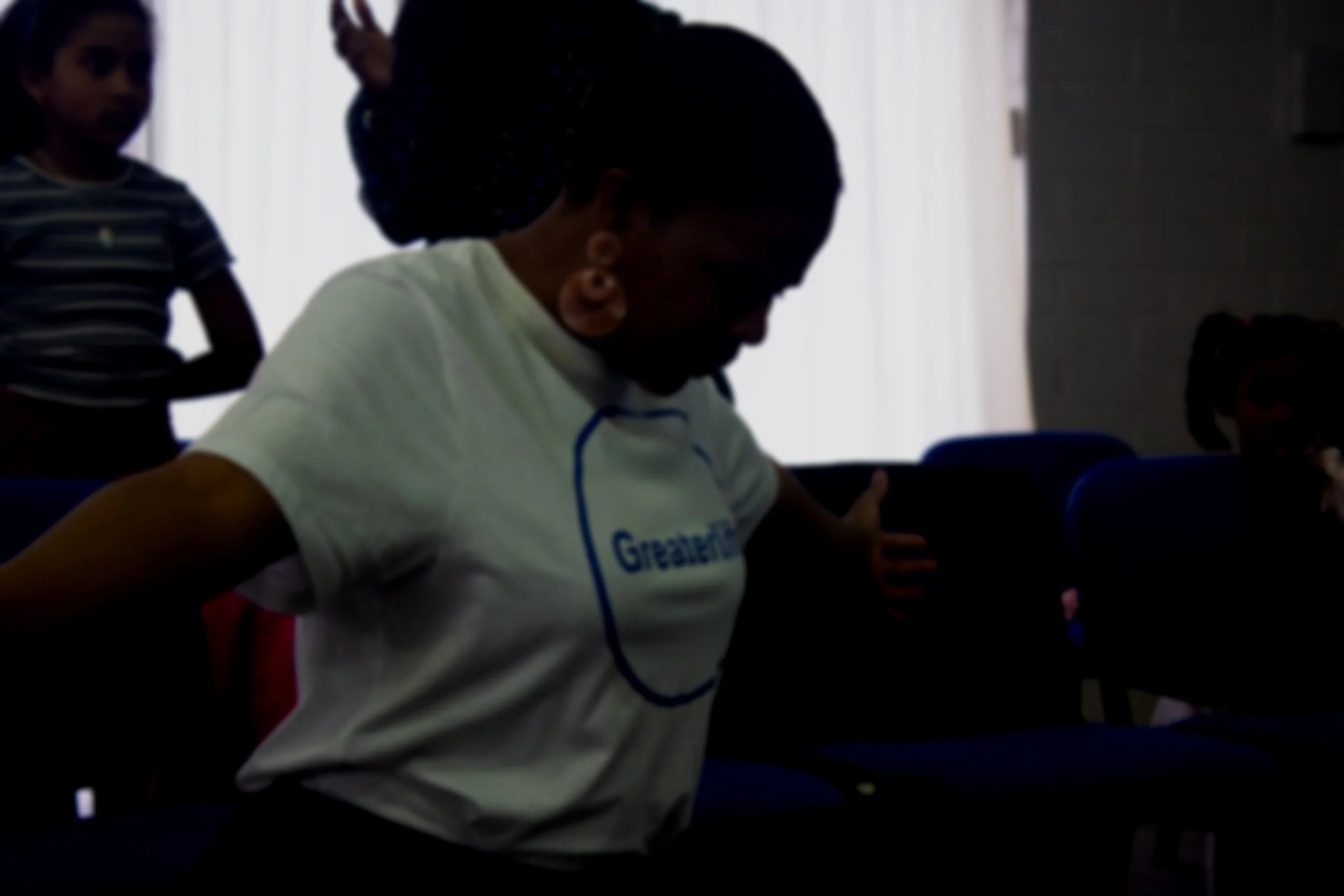 Sunlit mountain range with grassy hills in the foreground and a clear sky above.