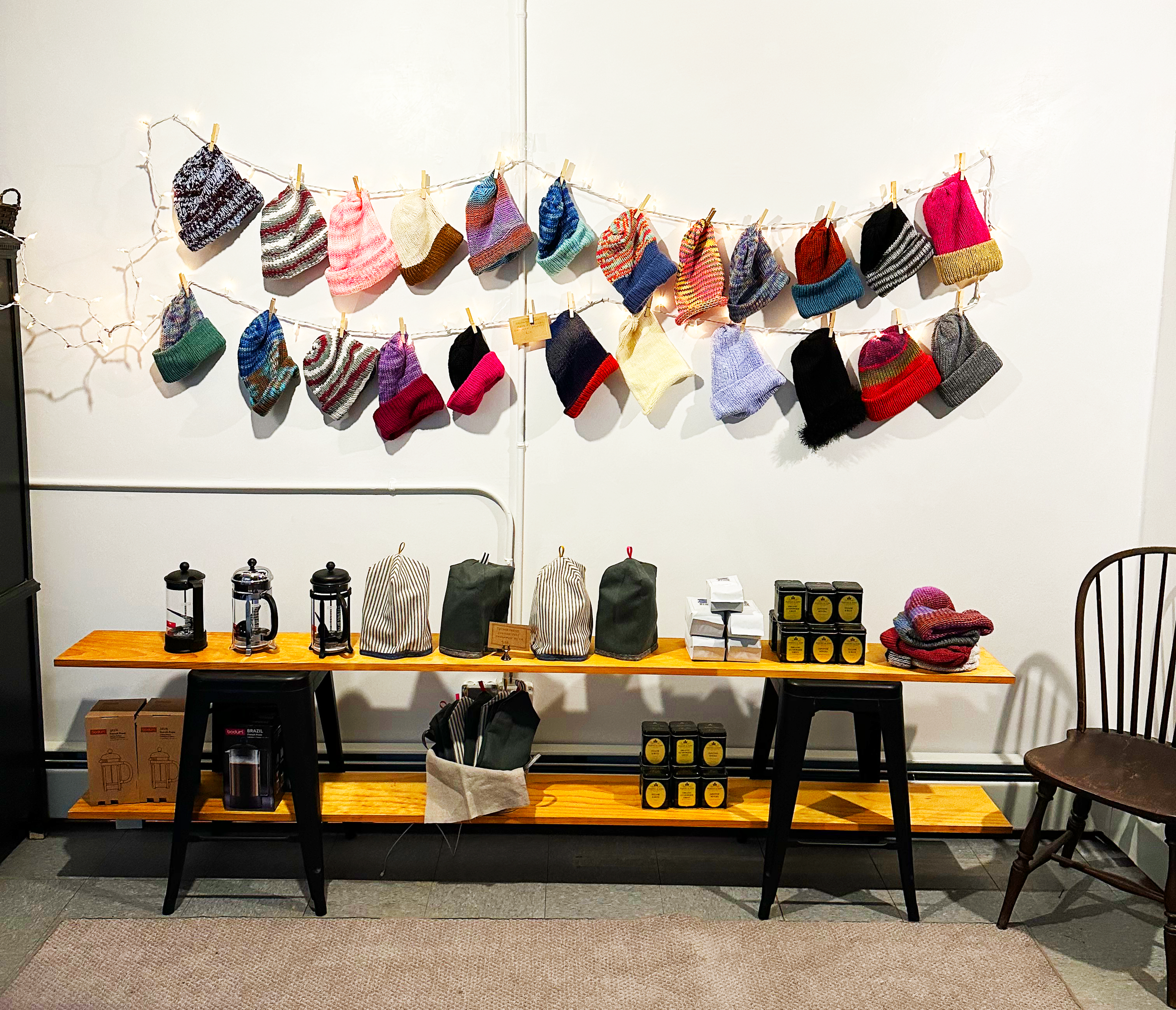 Inside the Mustard & Miel pop-up shop with colorful hand-knit hats pinned to twine above French presses, tea tins, and hand-sewn cozies.