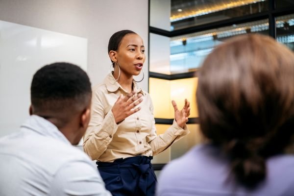 A photo of an employee in higher education communicating in person with her team, illustrating some of the factors involved in building supportive, neuro-inclusive department cultures.