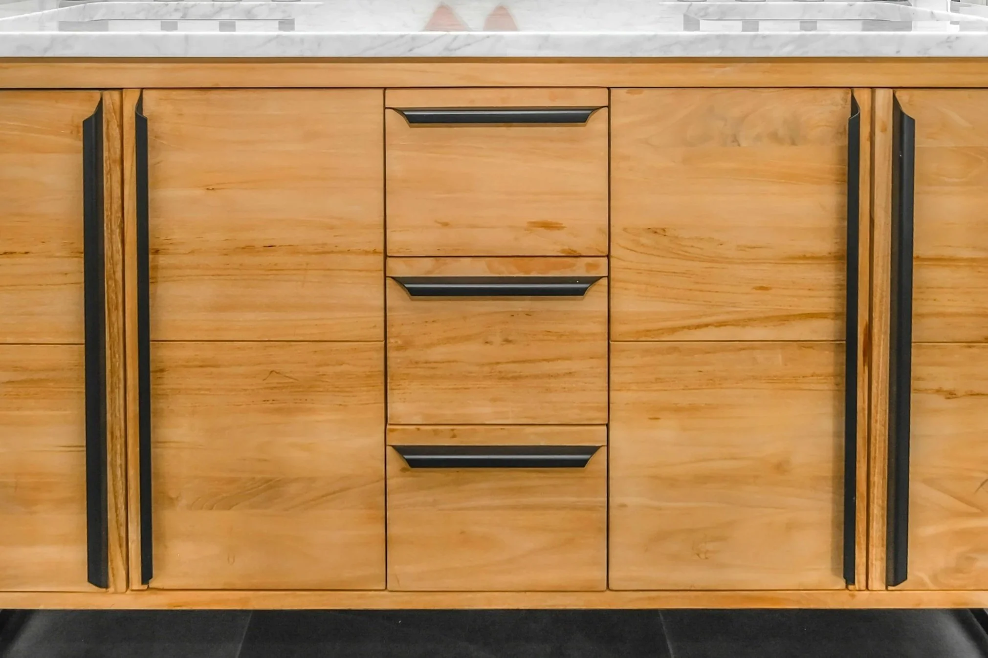 Wooden cabinet with black handles and a marble countertop.