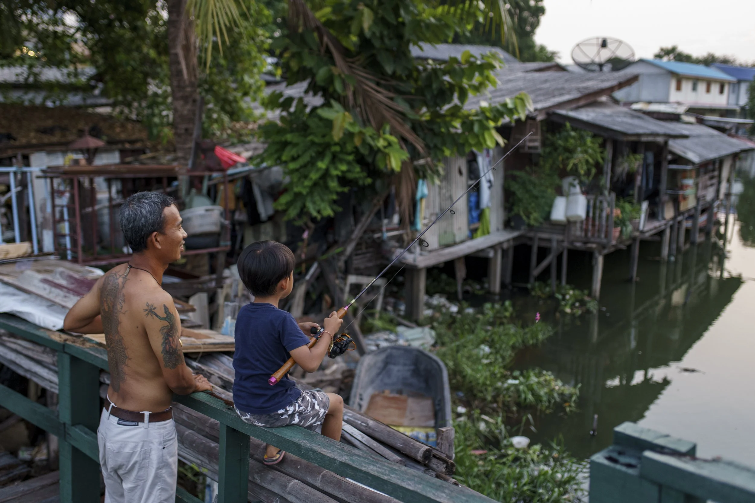 Father and son are fishing in the community's canal