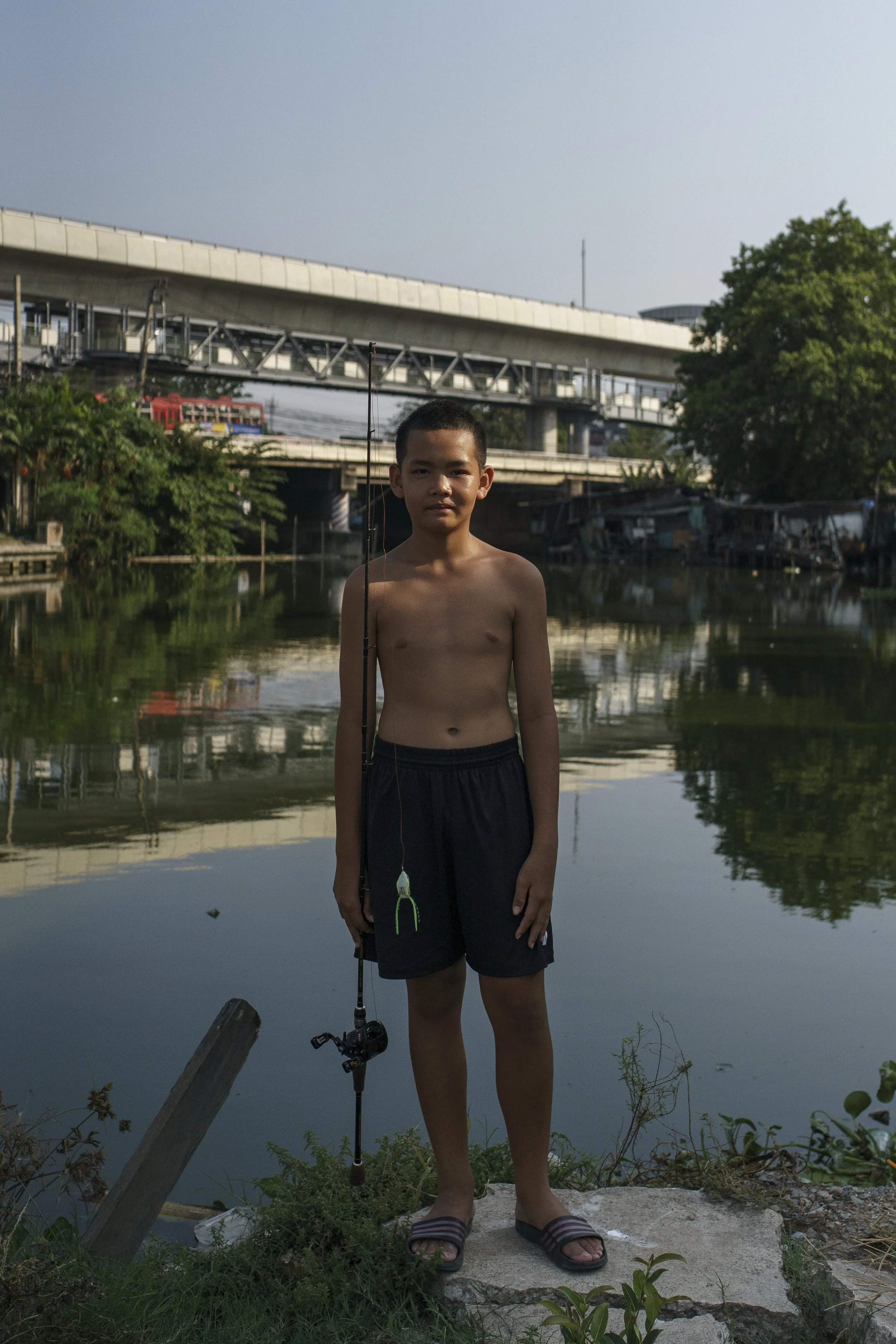 A boy posing for a photo while fishing in the community's canal