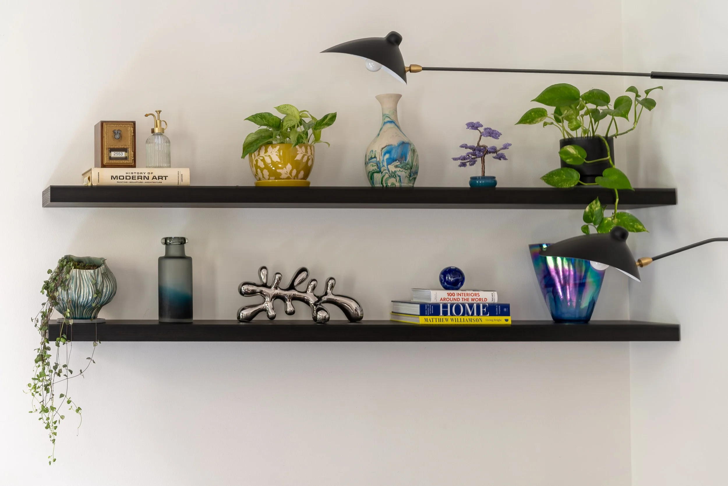 Eclectic floating shelf styling with decorative vases, plants, and sculptural decor in Old City Philadelphia.