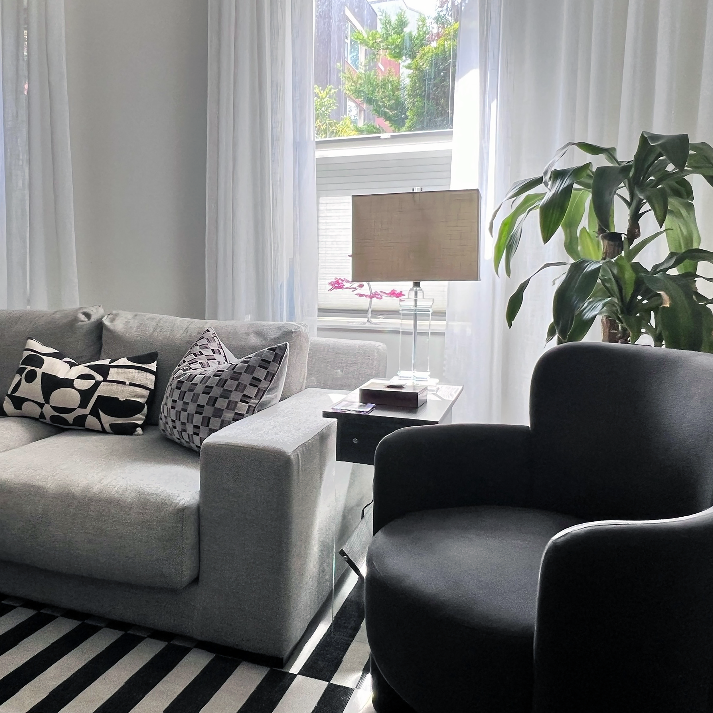 Contemporary living room with grey armchairs and striped rug.