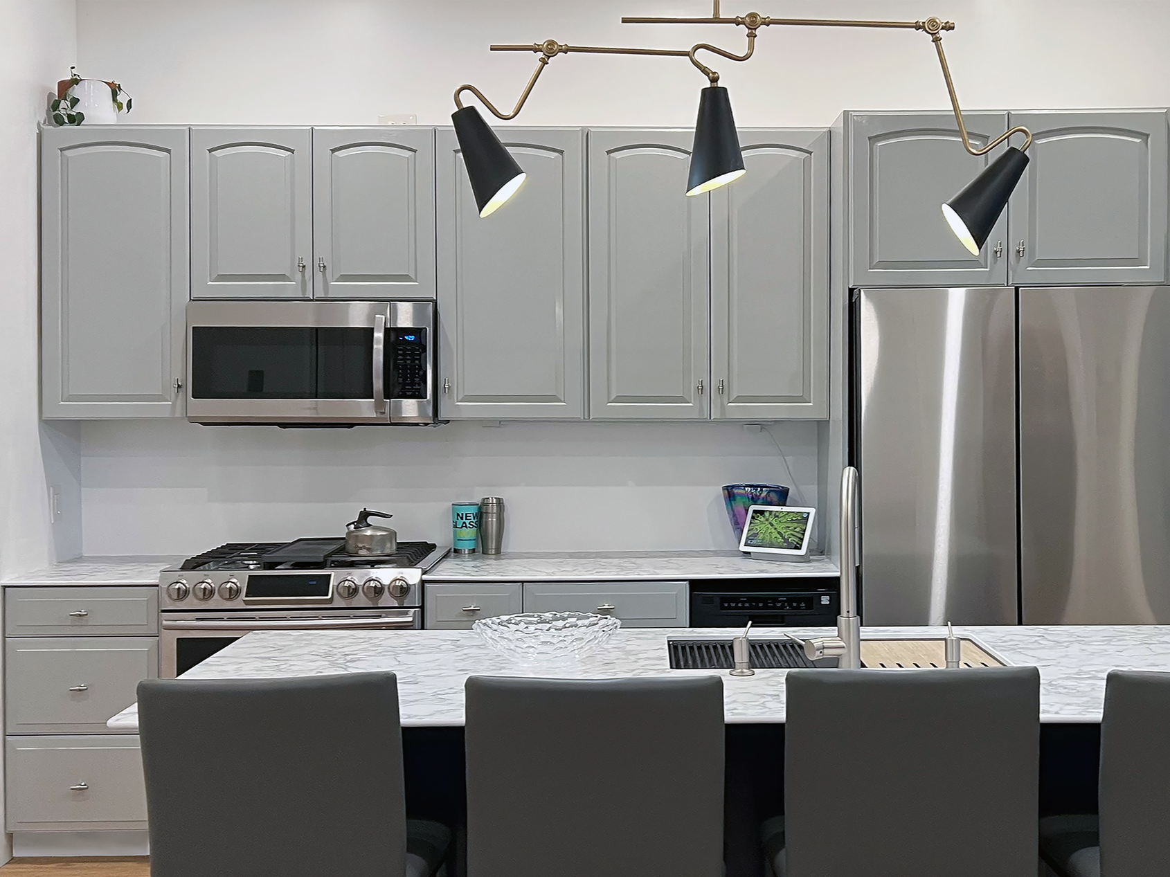 Full-service residential kitchen renovation in Philadelphia designed by Austin Seeley, showcasing custom gray cabinets, marble waterfall island, brass lighting, and space-efficient layout with integrated washer and dryer.