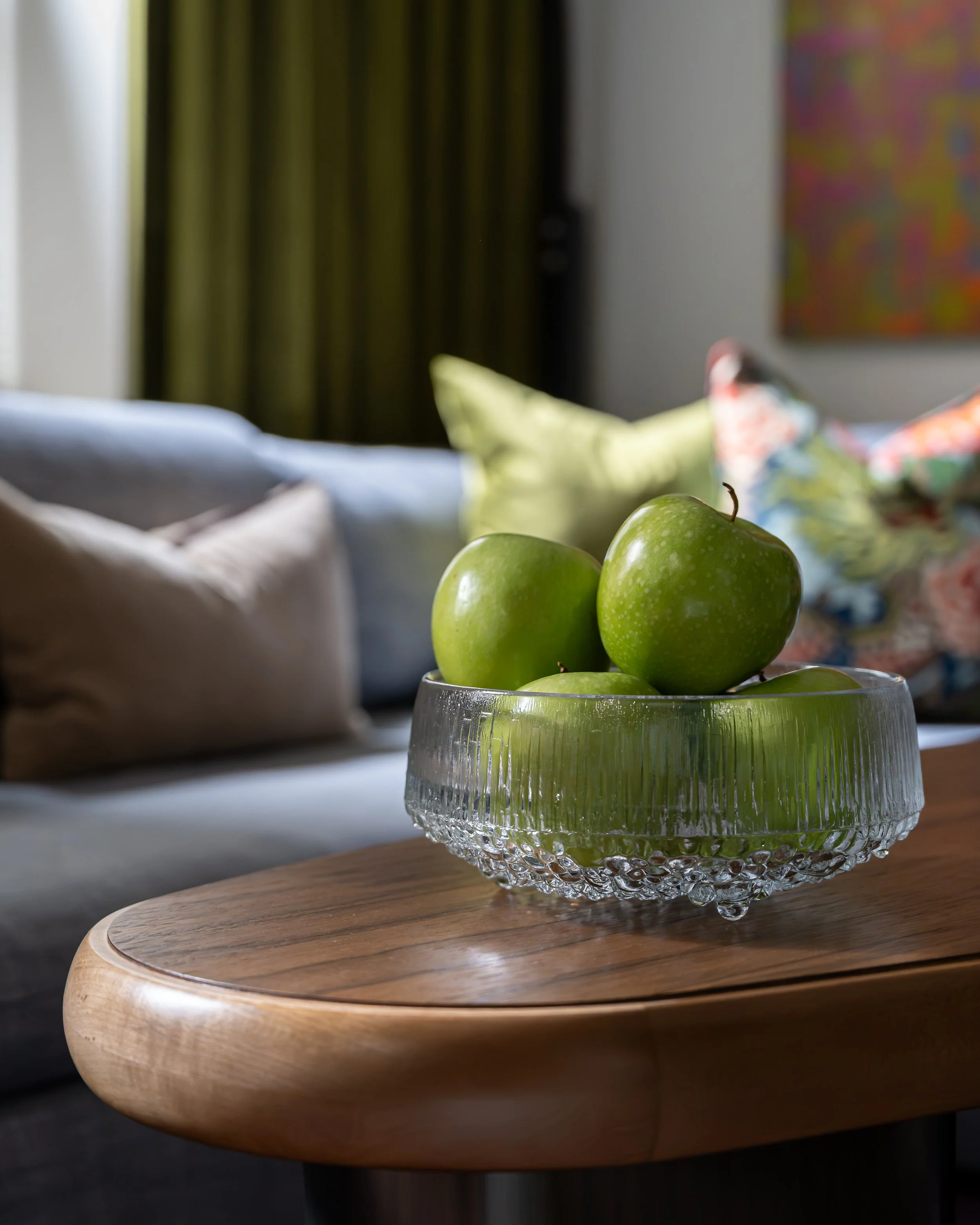 Green apples in a textured glass bowl on a wood coffee table in an eclectic Old City Philadelphia living room.