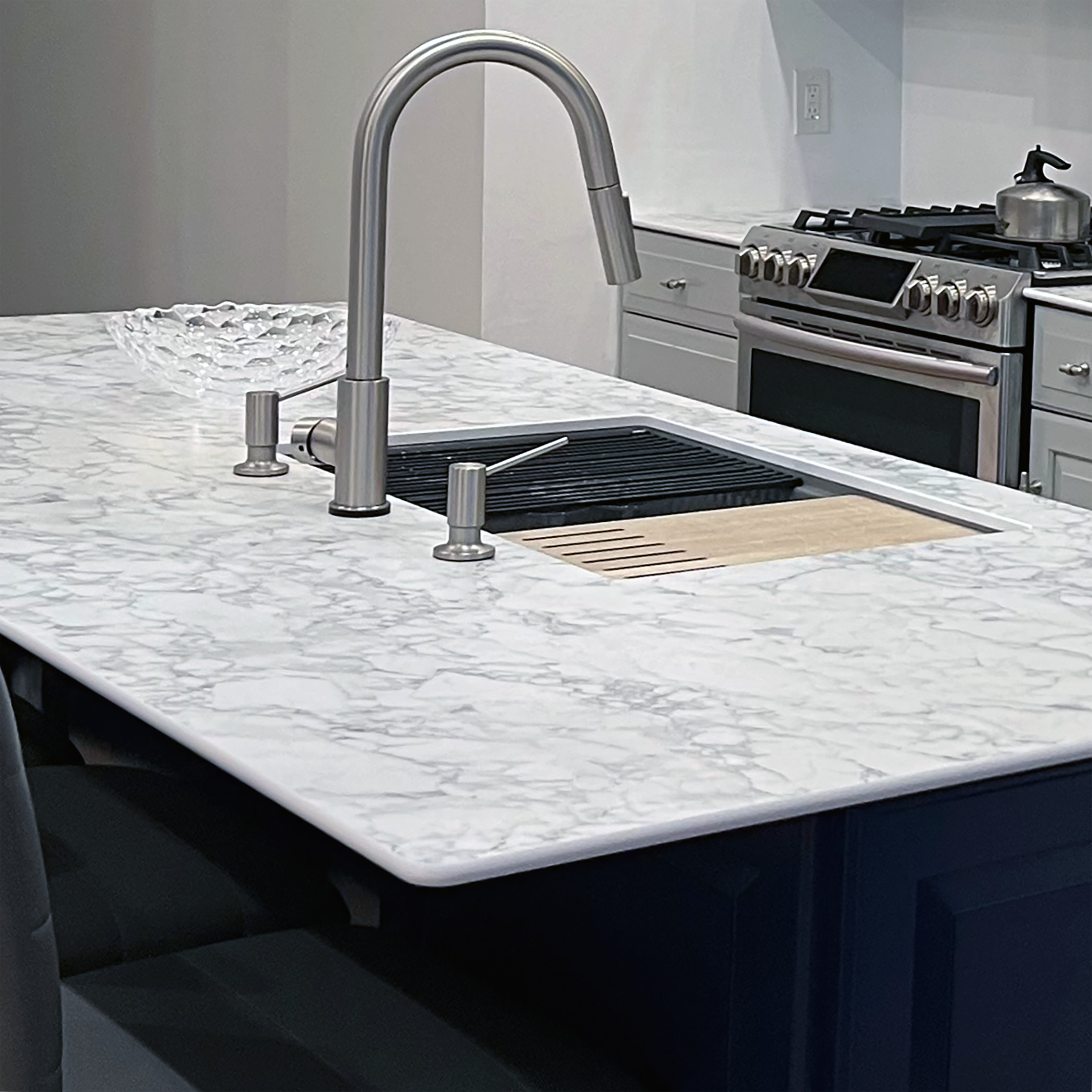 Close-up of marble-look kitchen island with integrated sink and cooktop in Corning Apartment 101 renovation.