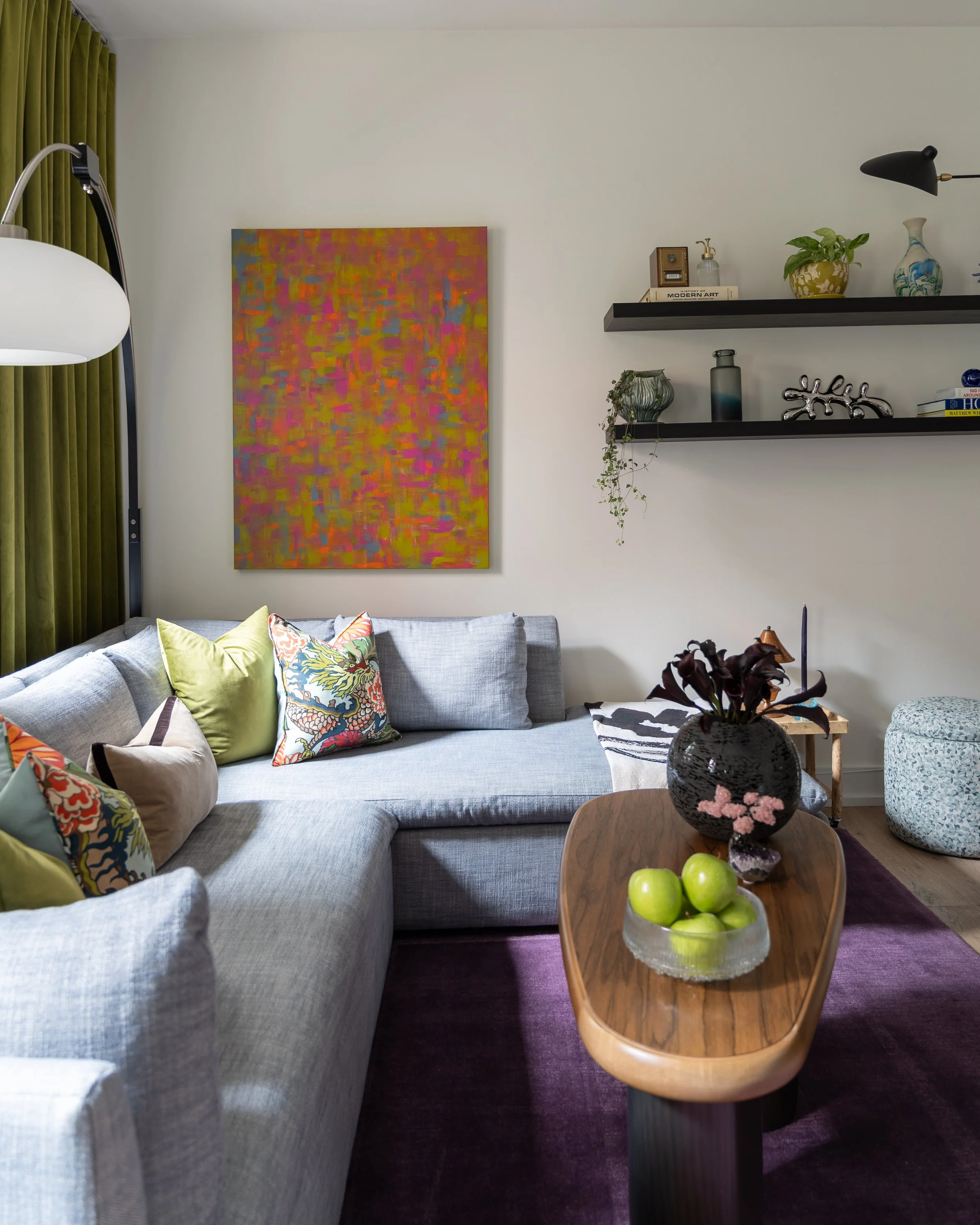 Eclectic Old City Philadelphia living room design with gray sectional, colorful abstract art, and purple rug.