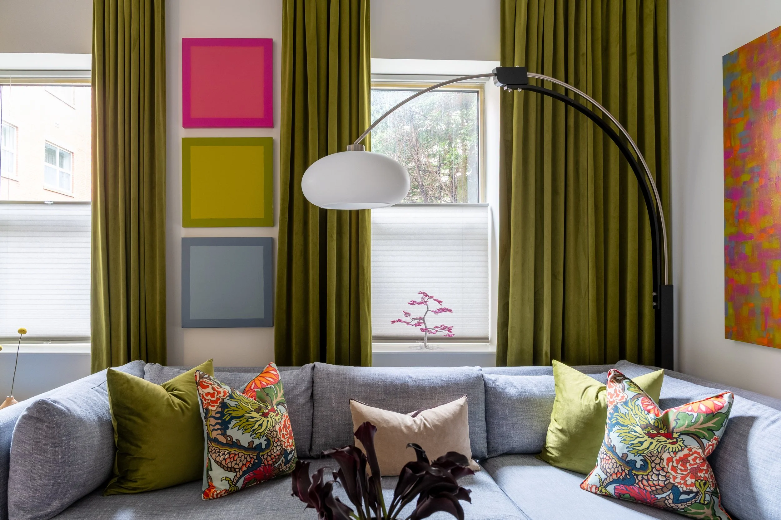 Colorful Old City Philadelphia living room with gray sectional, patterned pillows, olive curtains, and art.
