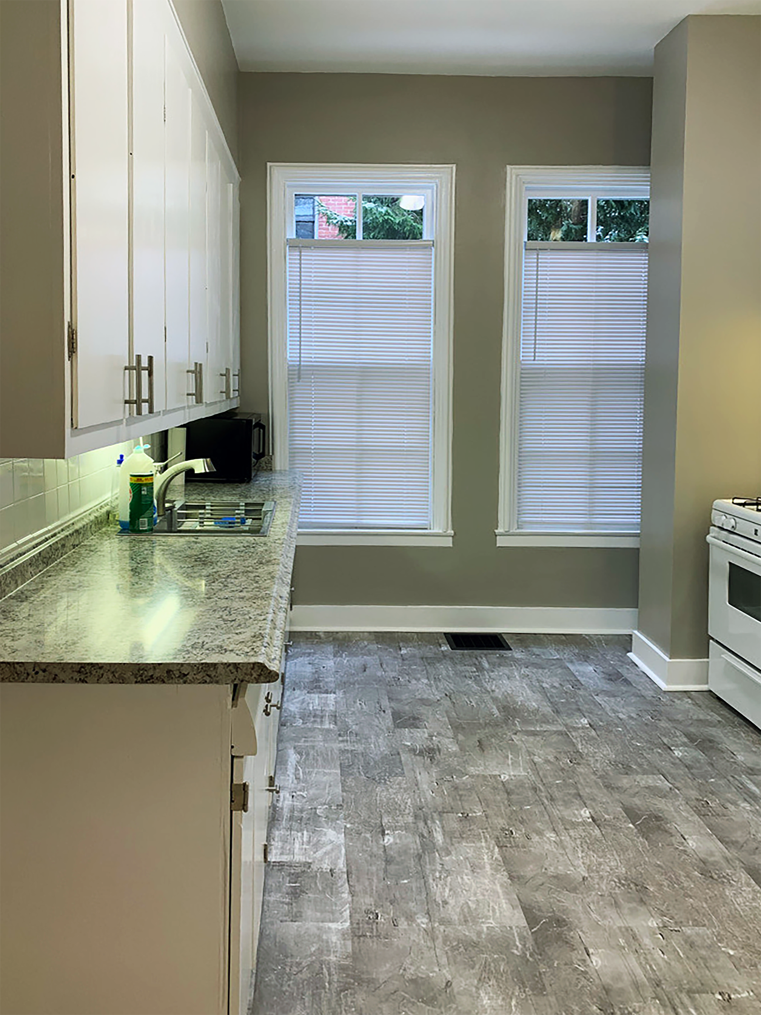 Updated galley kitchen with white cabinets, granite-like countertops, and modern lighting.