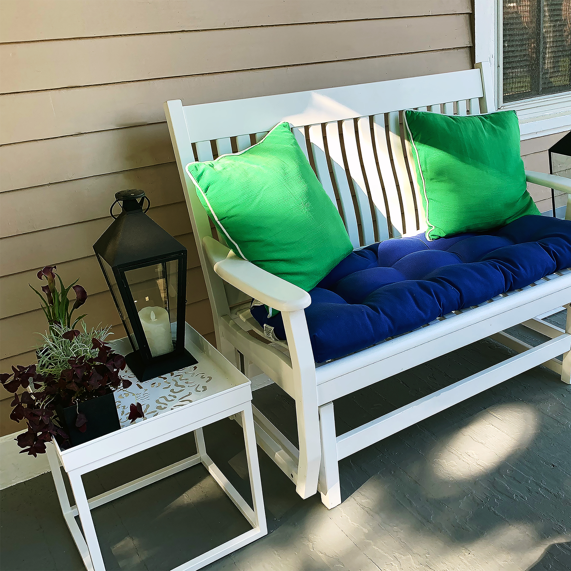 Sunlit porch with blue and green outdoor chairs.