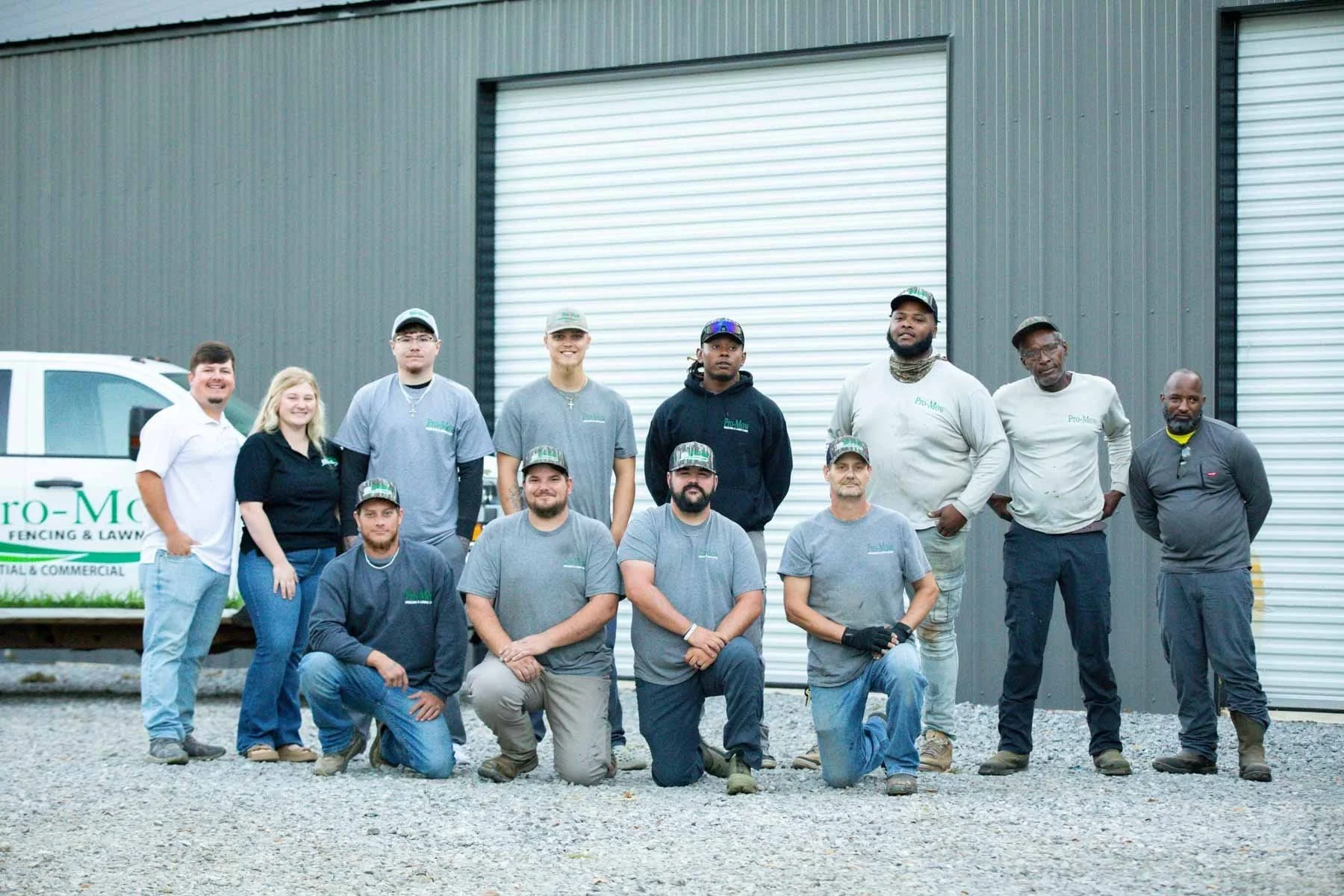 The Pro-Mow Lawn Care team in Alexandria, LA posing by a building and truck with the Pro-Mow logo.