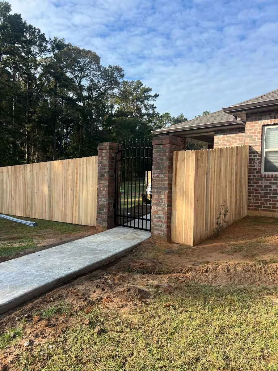 A new concrete path leading to a fence gate, installed by Alexandria, LA Pro-Mow landscape company.