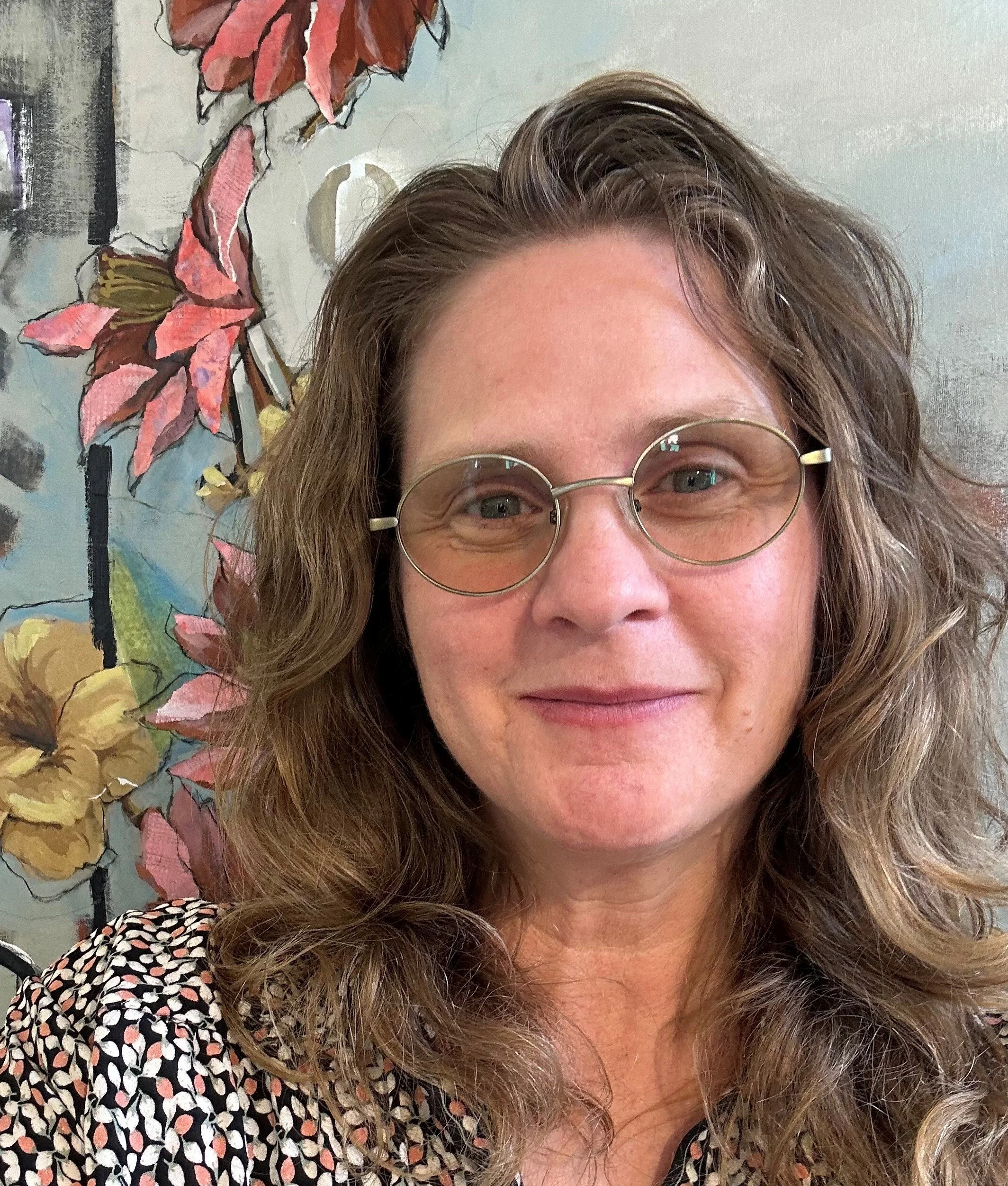 A woman with long brown hair and glasses.