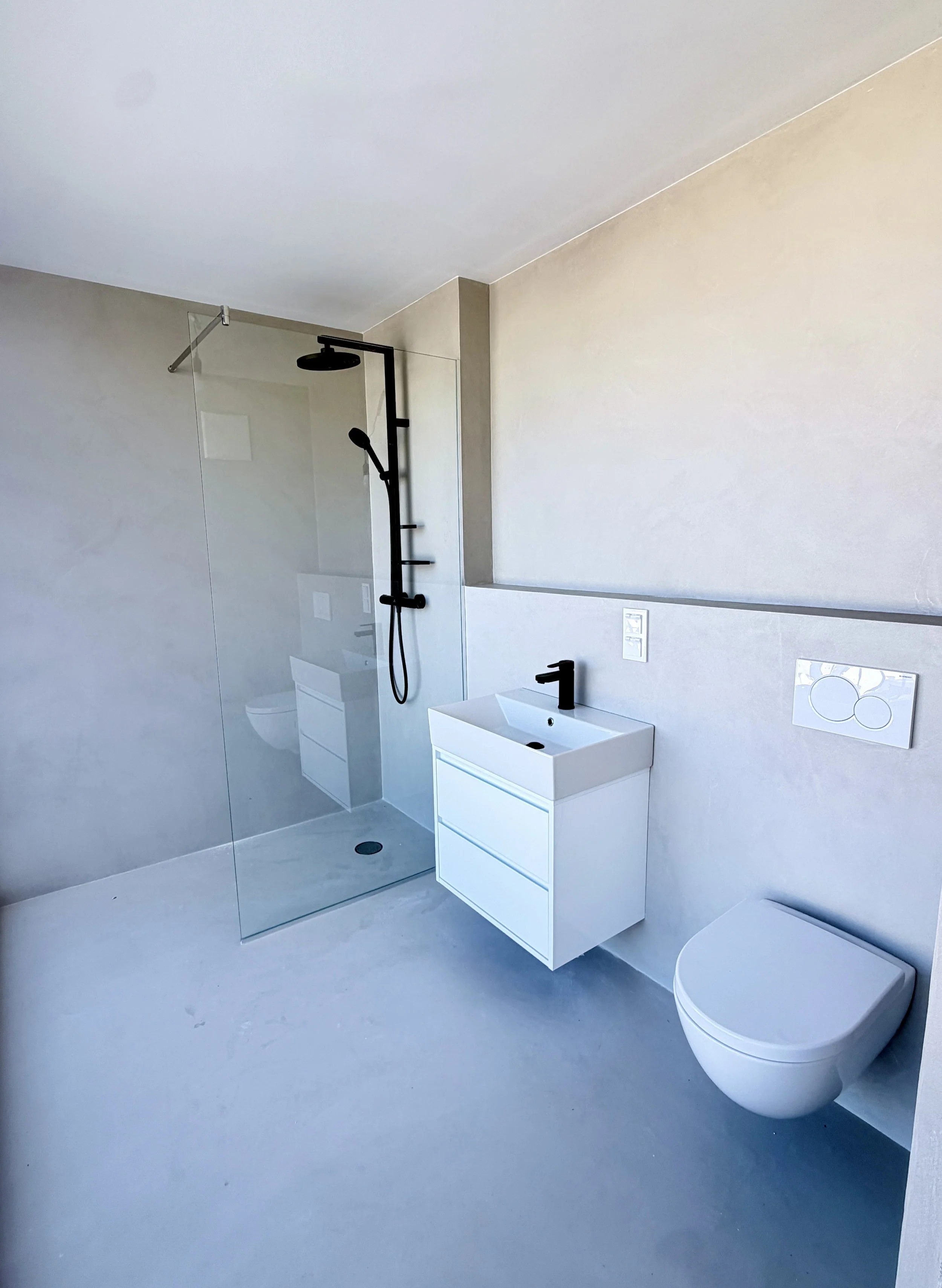 Modernes Badezimmer mit Dusche, Waschbecken und Toilette, in neutralen Farben, minimalistisch gestaltet.