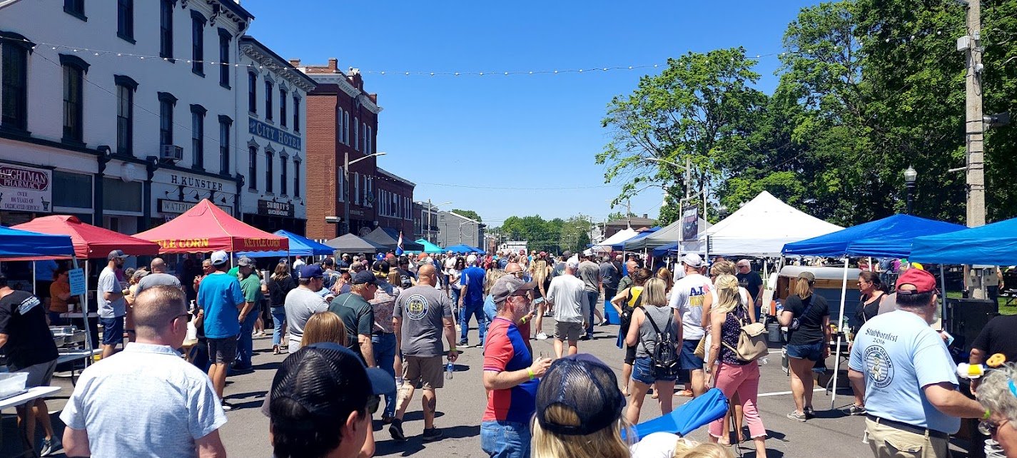 Crowd of people at the Beer-B-Que with vendor tents on a sunny day.