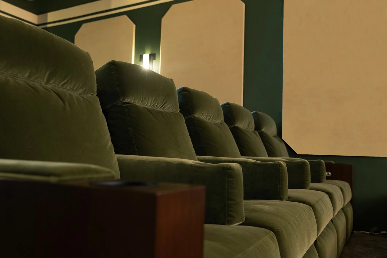 Rows of green theater or cinema seats in a dimly lit screening room.