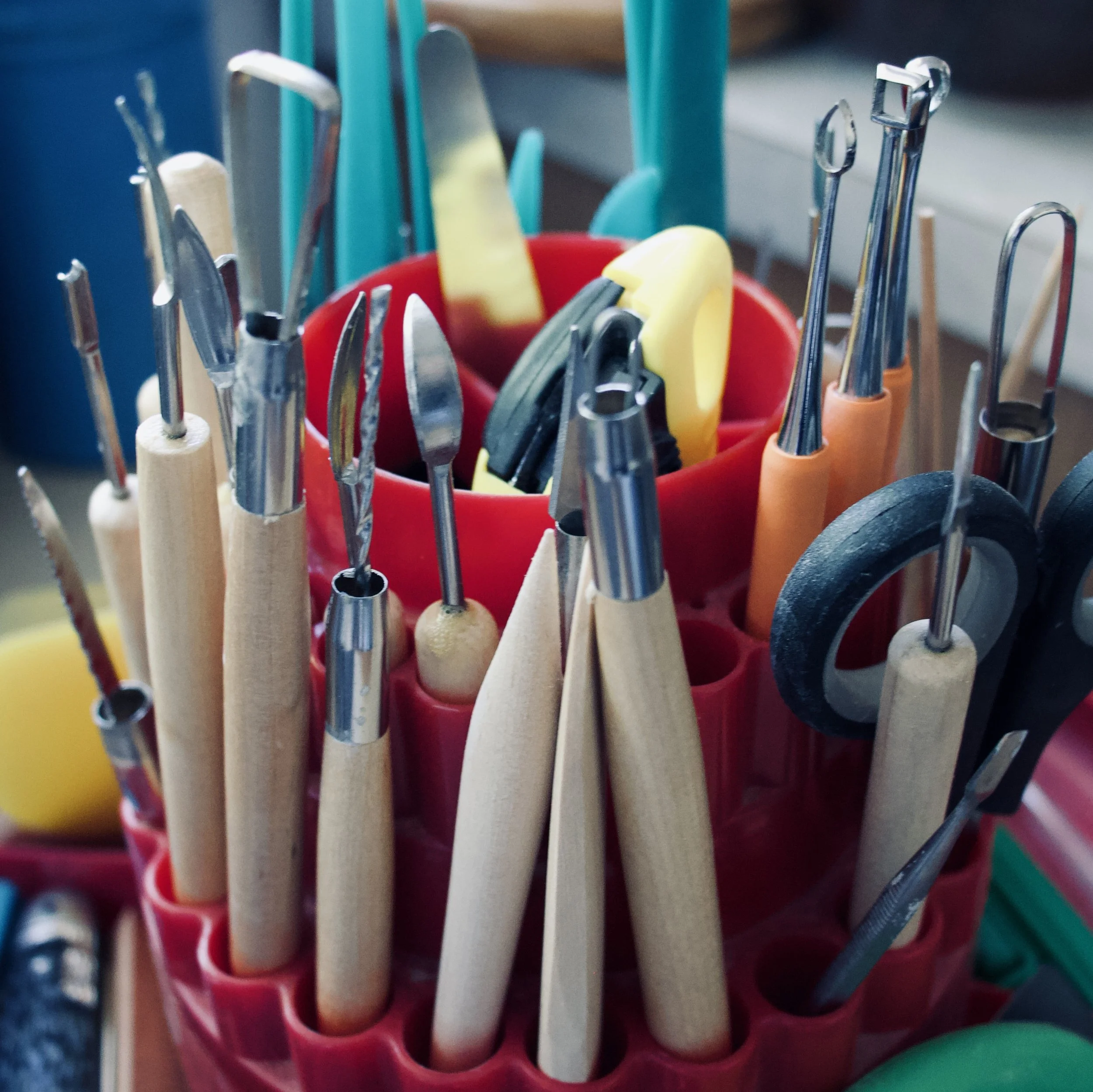 A variety of woodworking tools, including chisels, screwdrivers, and scissors, organized in a red plastic holder.