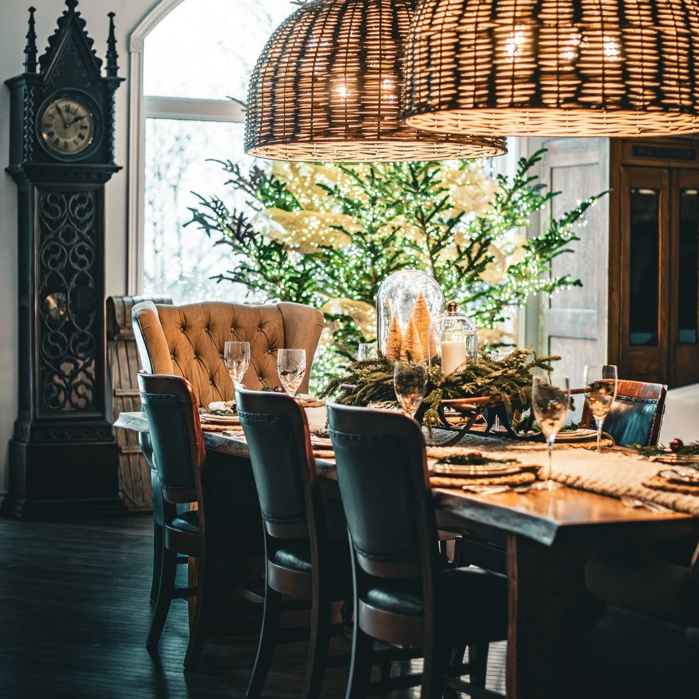 A table dusted with holiday magic ✨.  At its centre rests a charming child-sized sleigh, wrapped in a lush garland and topped with two glass cloches brimming with festive charm. Everything is layered over a chunky, beige knit table runner that brings