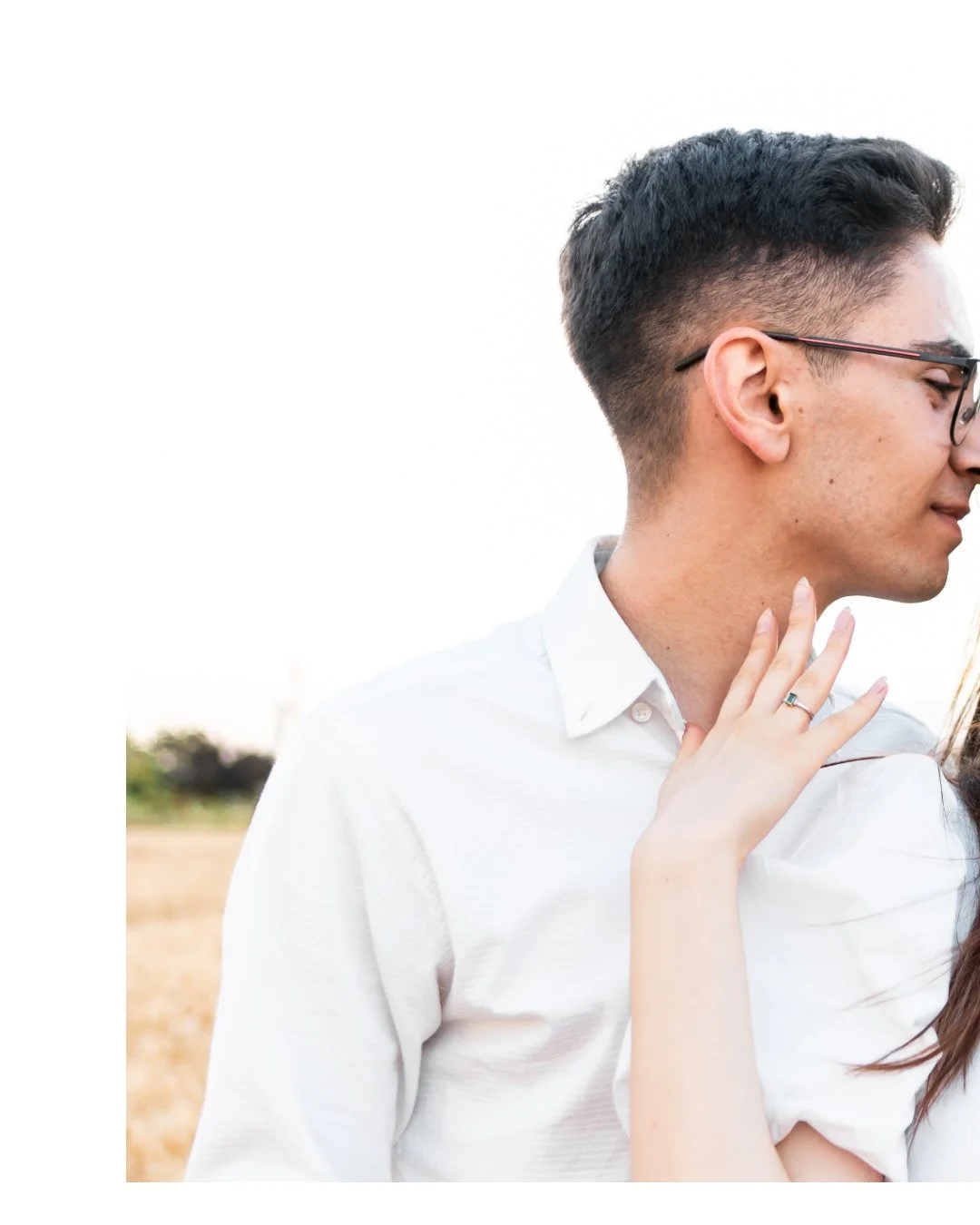 Profile of a young man with glasses and short dark hair, wearing a white shirt, outdoors during the day.