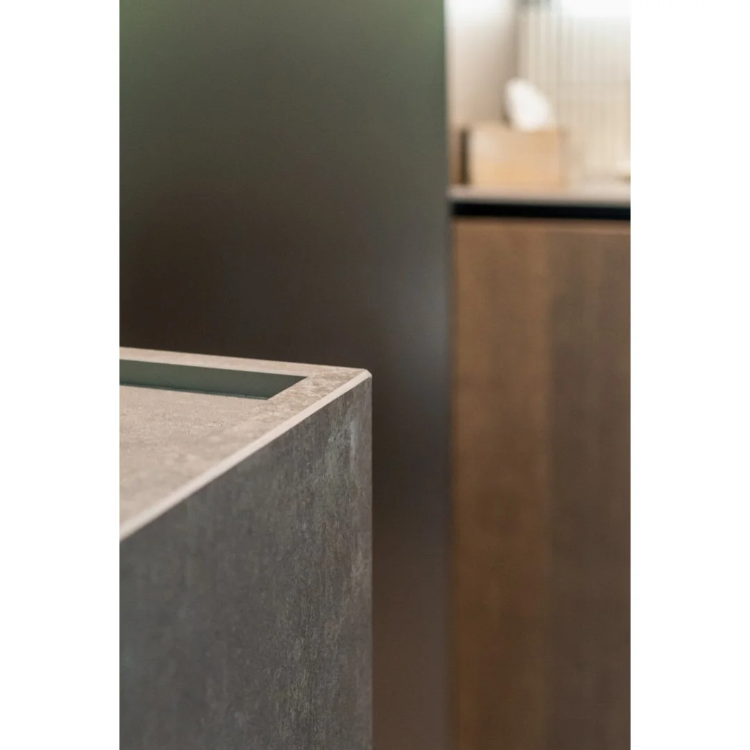 Close-up of a gray granite countertop with a soft background featuring a wooden cabinet and a dark wall.